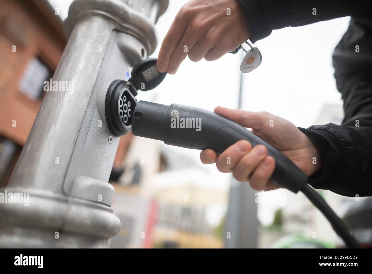 Berlin, Deutschland. September 2024. Ein Mann steckt einen Stecker zum Aufladen eines Elektroautos auf dem EUREF-Campus in eine Ubitricity-Ampelpfosten-Ladestation. Diese Ladestationen sind jedoch in Deutschland nicht zugelassen, werden aber in den Niederlanden und im Vereinigten Königreich eingesetzt. Quelle: Sebastian Gollnow/dpa/Alamy Live News Stockfoto