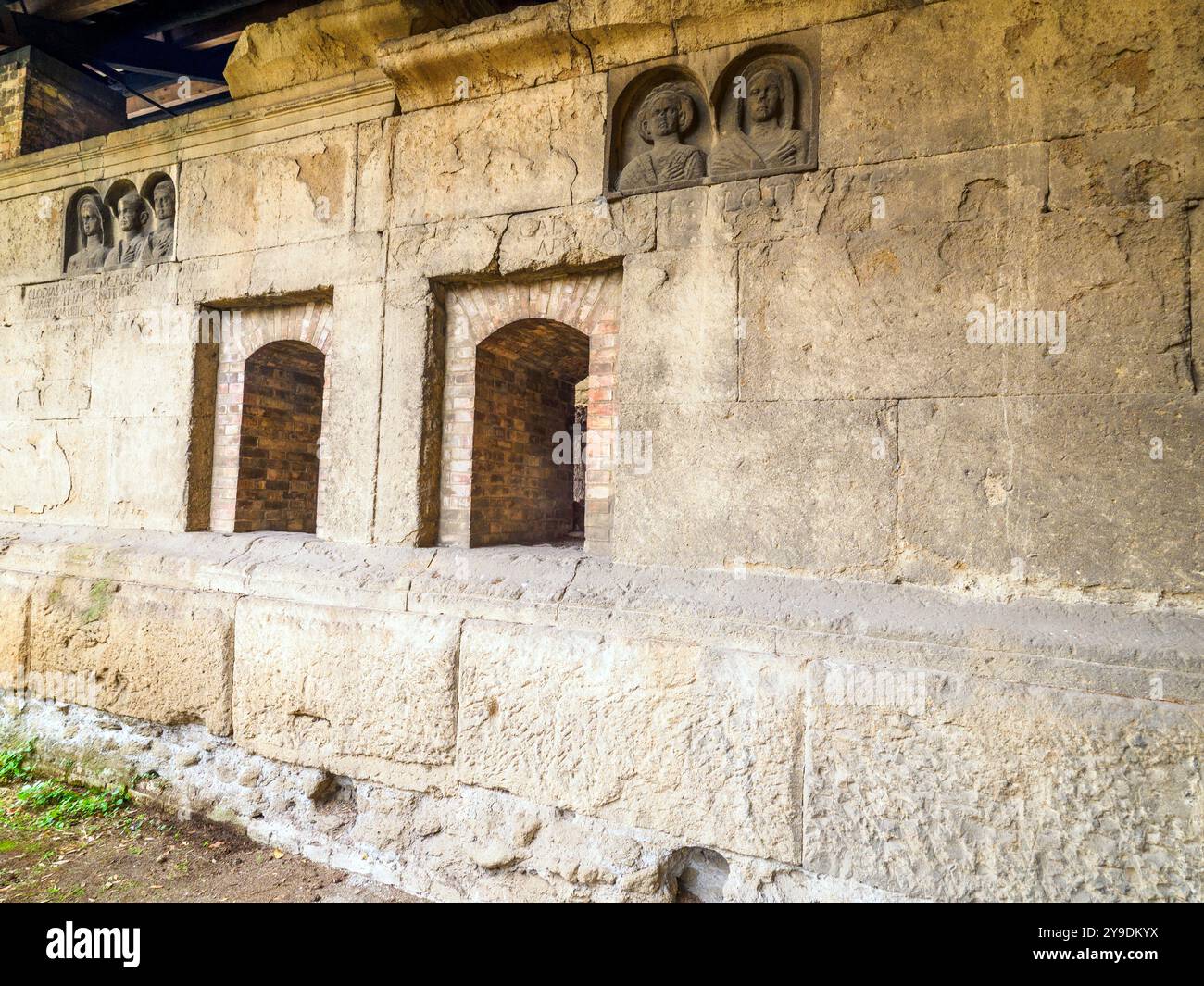 Das Detail des Grabes „Gemino Sepulchre“, das auf sechs verschiedene Freigelassene der Familien Clodia, Marcia und Annia Bezug nimmt und auf den Anfang des 1. Jahrhunderts v. Chr. datiert ist, besteht aus zwei Zellen, die über kleine Türen zugänglich sind, die sich nach außen auf eine Fassade öffnen, die von einem Tufffuß mit Skulpturen von Verstorbenen gekennzeichnet ist. Republikanische Gräber an der Via Statilia – Rom, Italien Stockfoto