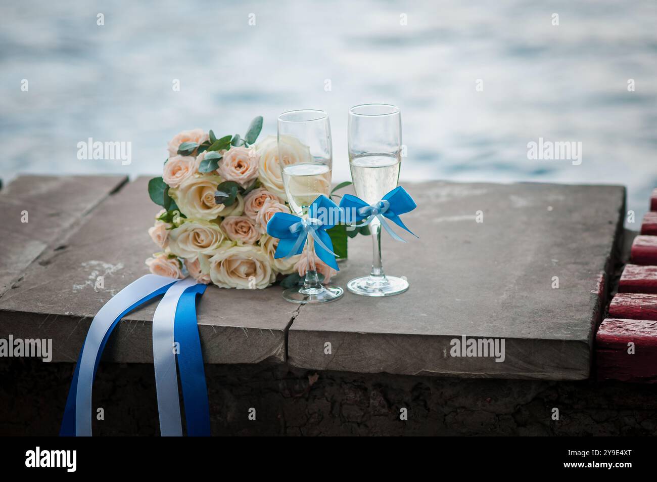 Elegant gestalteter Hochzeitsstrauß mit Toastgläsern am Water's Edge. Stockfoto
