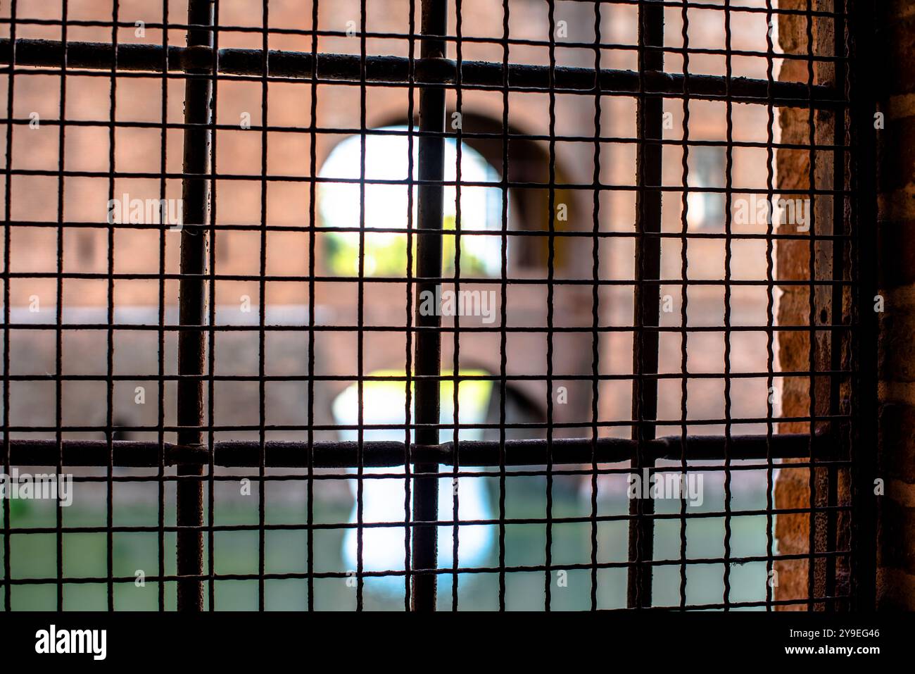 Fenster geschlossen durch Gitter mit Blick auf die Burg aus den Kerkern des Castello degli Estensi in Ferrara Italien Stockfoto