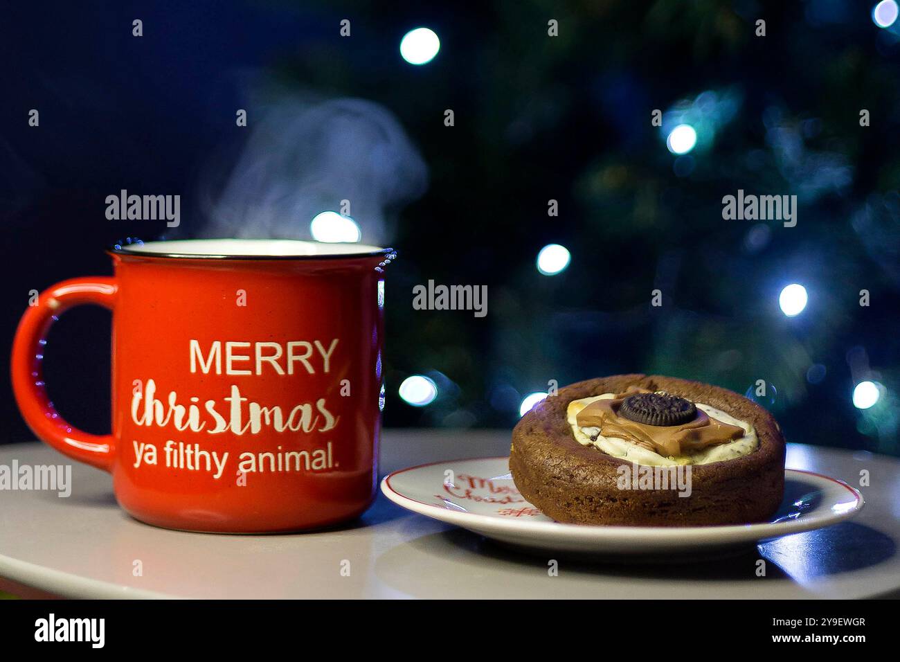 Weihnachtsbecher Merry Christmas Ya dreckiges Tier und Kekse auf dem Tisch. Bokeh-Weihnachtsbaum. Weihnachten Hintergrund Stockfoto