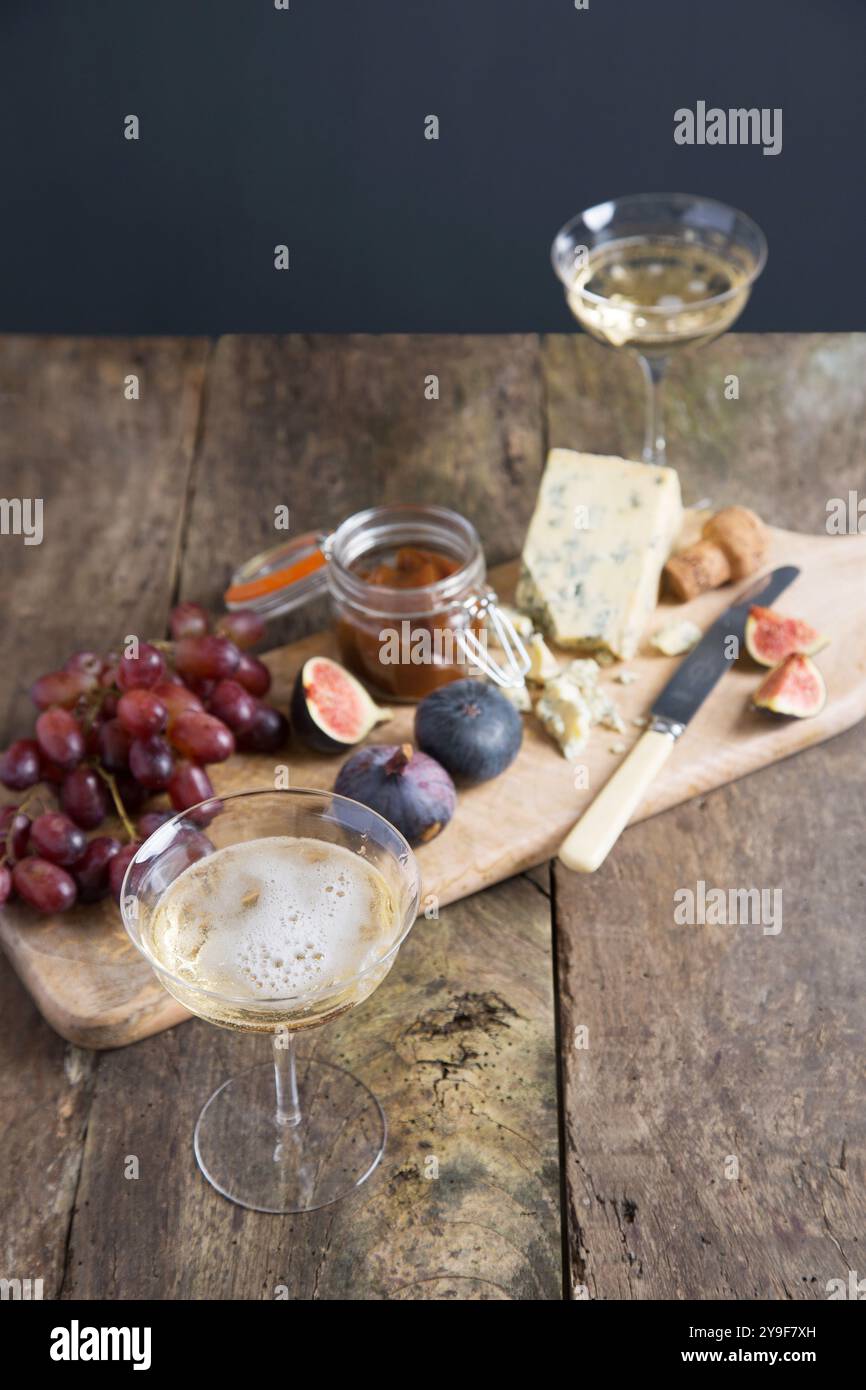 Eine perfekte Kombination aus Champagner, Feigen und Käse auf einem rustikalen Holzbrett, die die Essenz von Gourmet-Genuss und raffinierter Unterhaltung einfängt. Stockfoto