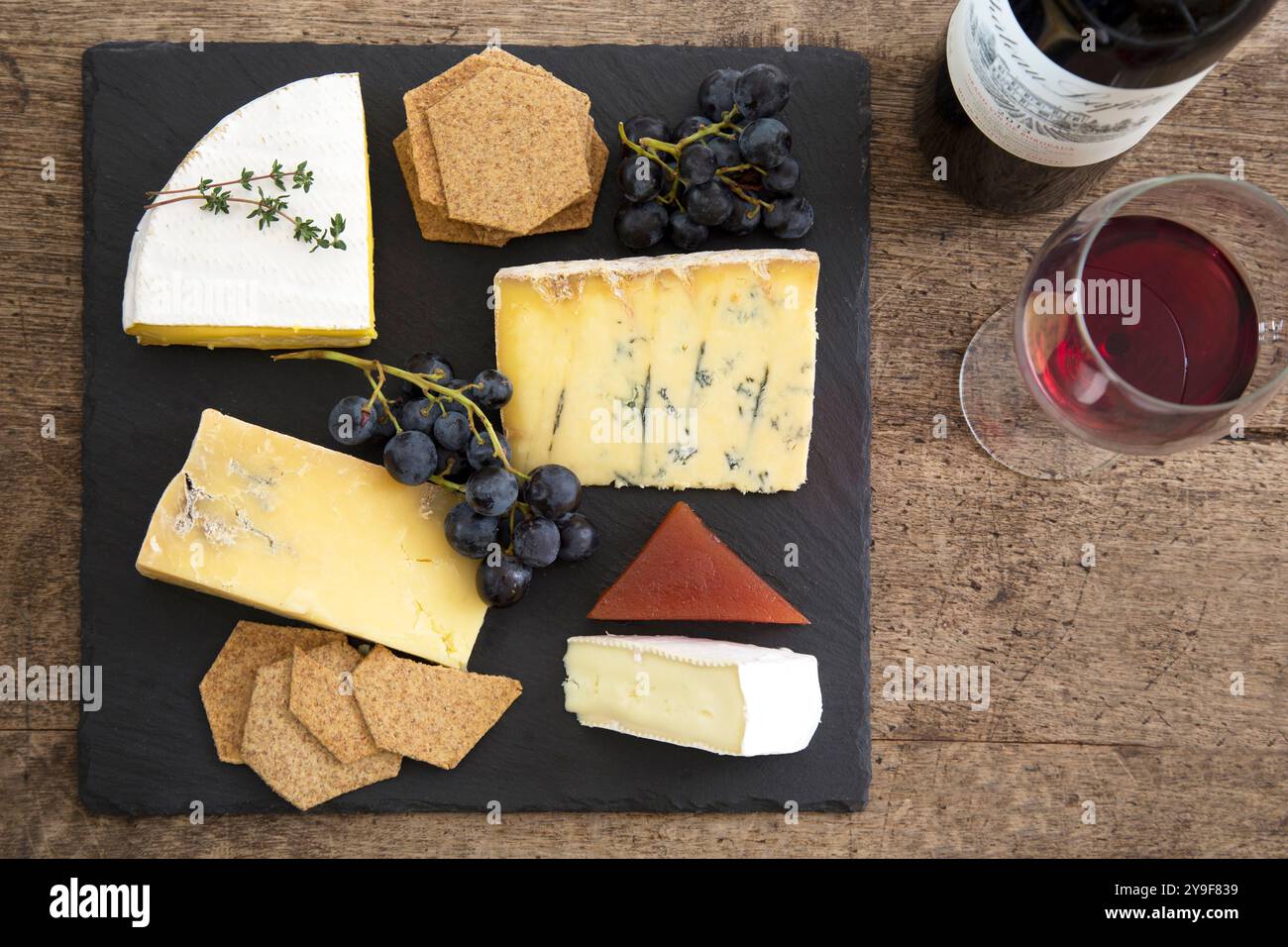 Ein elegantes Käsebrett mit handwerklicher Auswahl, Crackern und frischen Trauben, perfekt kombiniert mit einem Glas Rotwein für einen raffinierten Genuss Stockfoto