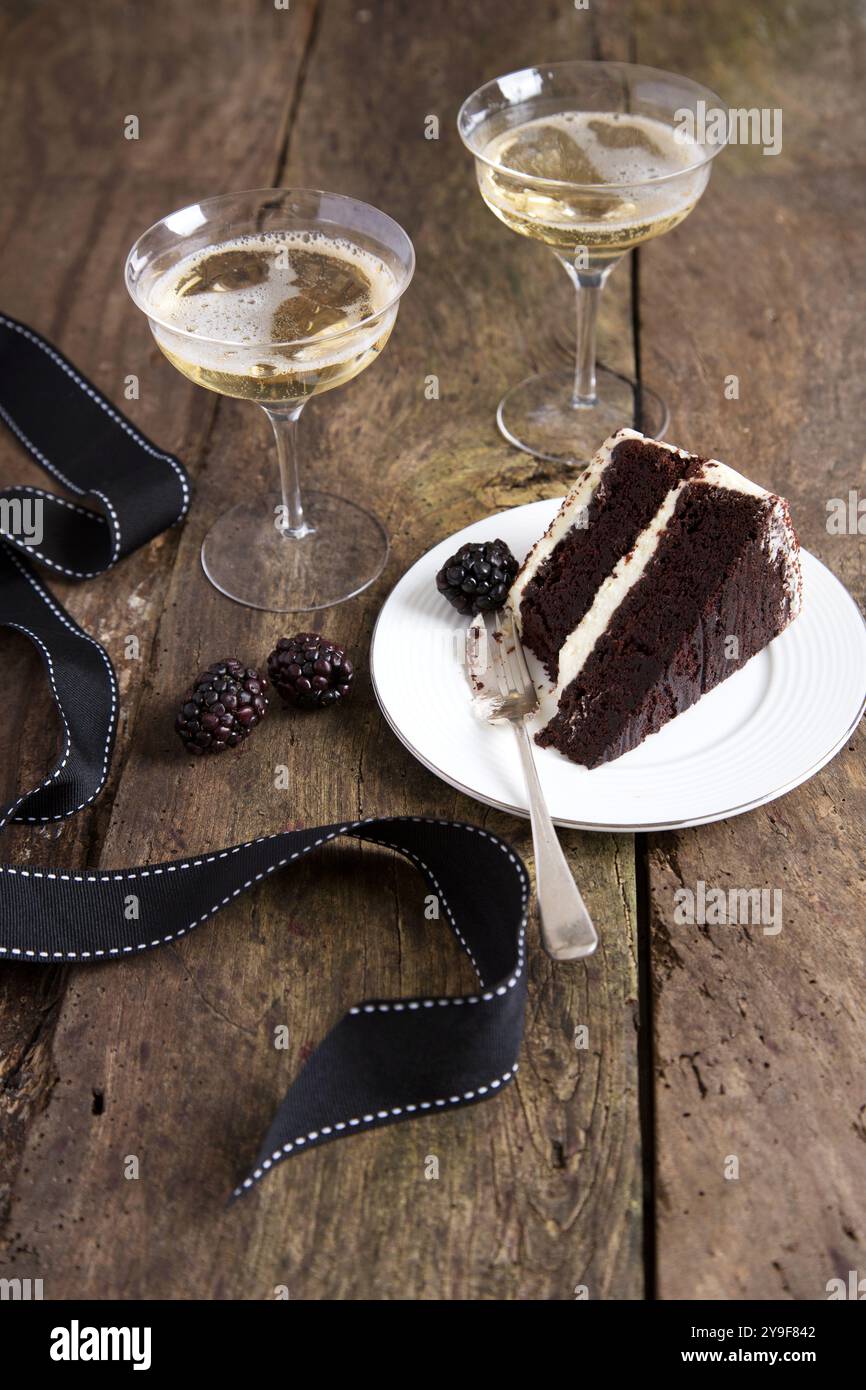 Feiern Sie stilvoll mit einer reichhaltigen Schokoladenkuchenscheibe und einem Glas Sekt – die perfekte Kombination aus Genuss und Eleganz. Stockfoto