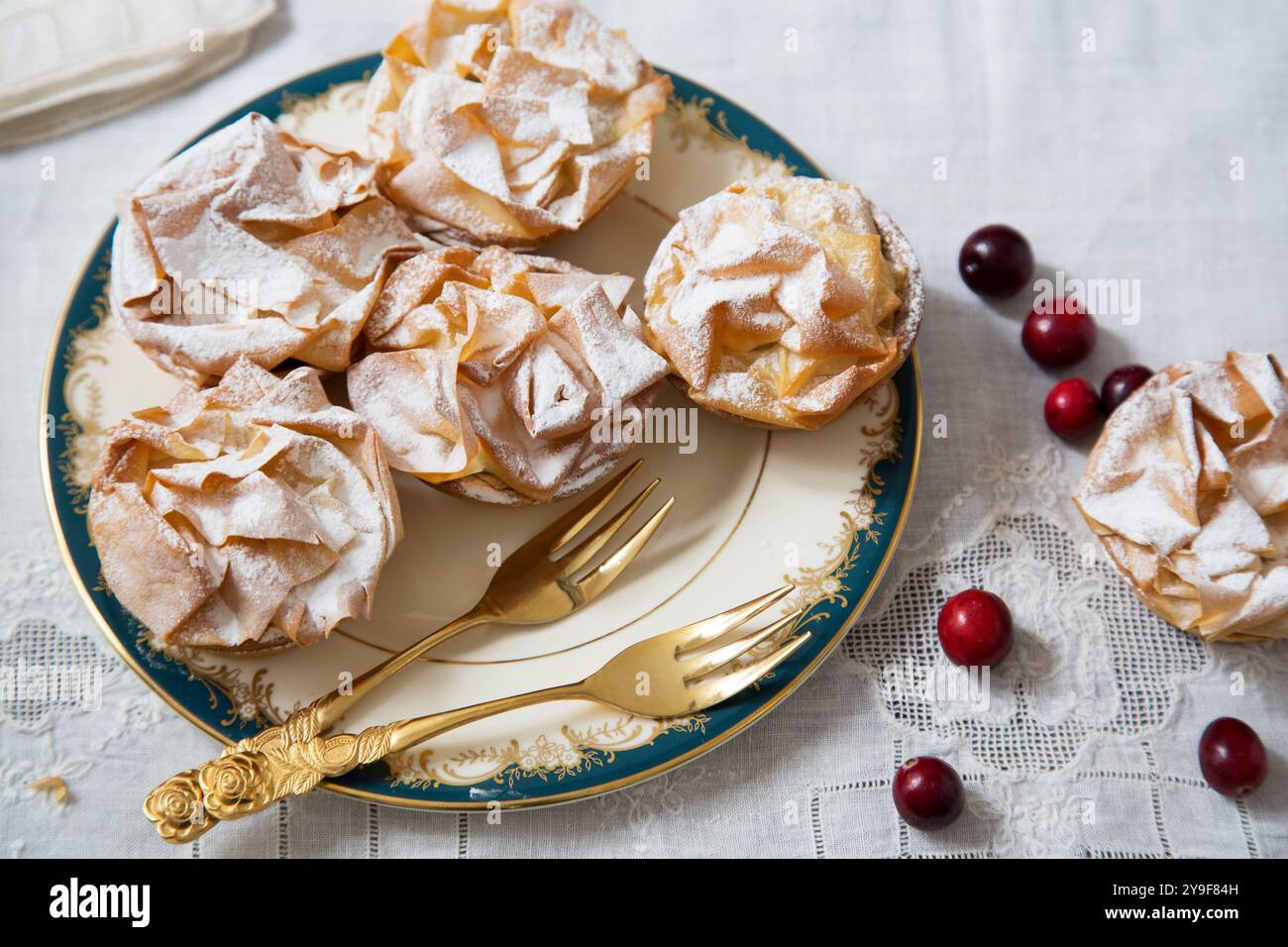 Zart gefertigte, edle Hackkuchen, mit Puderzucker bestäubt, serviert auf feinem porzellan mit goldenem Besteck, perfekt für eine luxuriöse Weihnachtsfeier Stockfoto