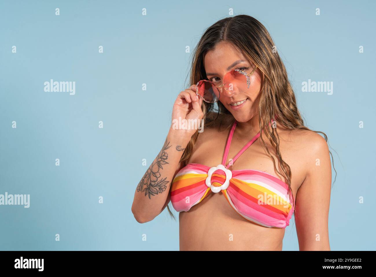Porträt der schönen brünetten Latina Frau mit langen Haaren, die vor der Kamera in einer flirtenden Haltung mit Brille und einem Bikini mit Rot posiert Stockfoto