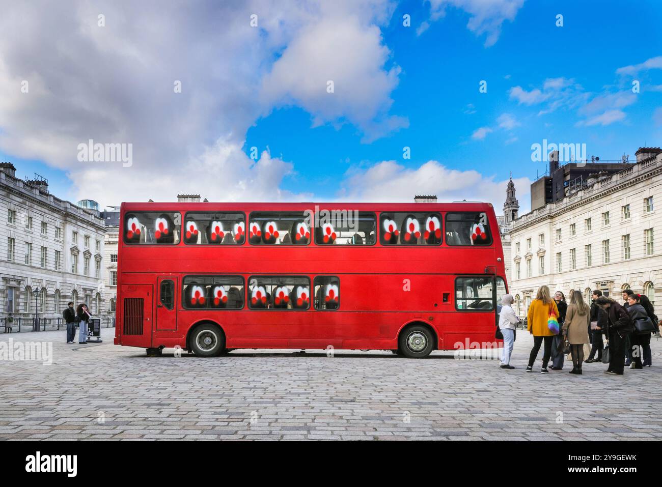 London, Großbritannien. Oktober 2024. Besucher mit der zentralen Hofinstallation, die ursprünglich zwei Busse haben sollte, nicht einen. Im Innenhof des Somerset House wurde eine monumentale Installation aus lebensgroßen Londoner Bussen vom Künstler Slawn enthüllt. In den Doppeldeckerbussen des britisch-nigerianischen Künstlers Slawn mit Graffigeband erkunden Sie die Erreichbarkeit und die soziale Verbindung. 1-54 die Contemporary African Art Fair feiert ihre 12. Auflage im Somerset House mit der Sonderinstallation. Quelle: Imageplotter/Alamy Live News Stockfoto