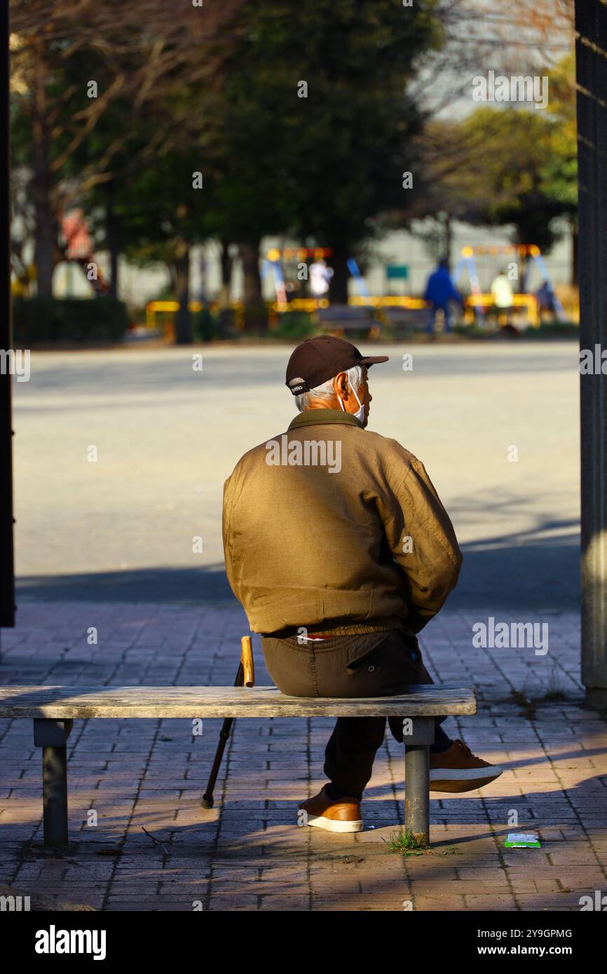 Das tägliche Leben in Japan ein älterer Mann, der sich nachmittags auf einer Parkbank entspannt Stockfoto