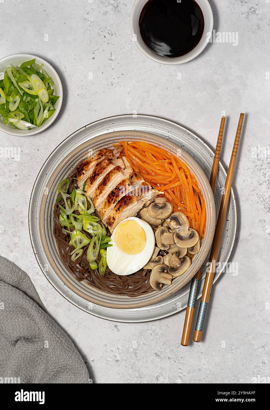 Lebensmittelfotografie von Suppen-Ramen mit Huhn, Soba, Buchweizennudeln, Ei, Pilz, Frühlingszwiebeln und Karotten, Essstäbchen Stockfoto