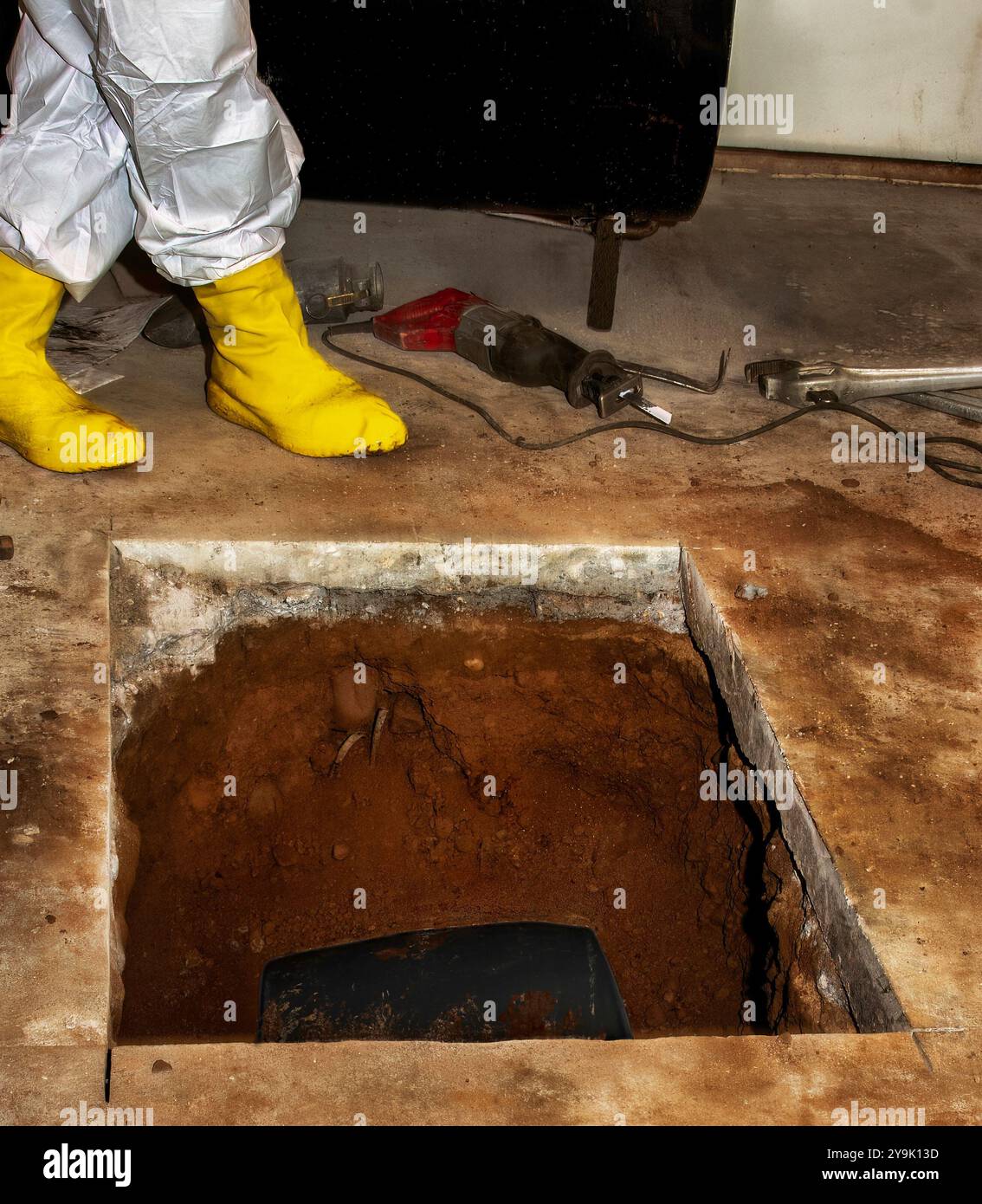 Ausbau des Öltanks: Arbeiter schneidet in Betonboden, um den vergrabenen Öltank für die Stilllegung freizulegen. Stockfoto