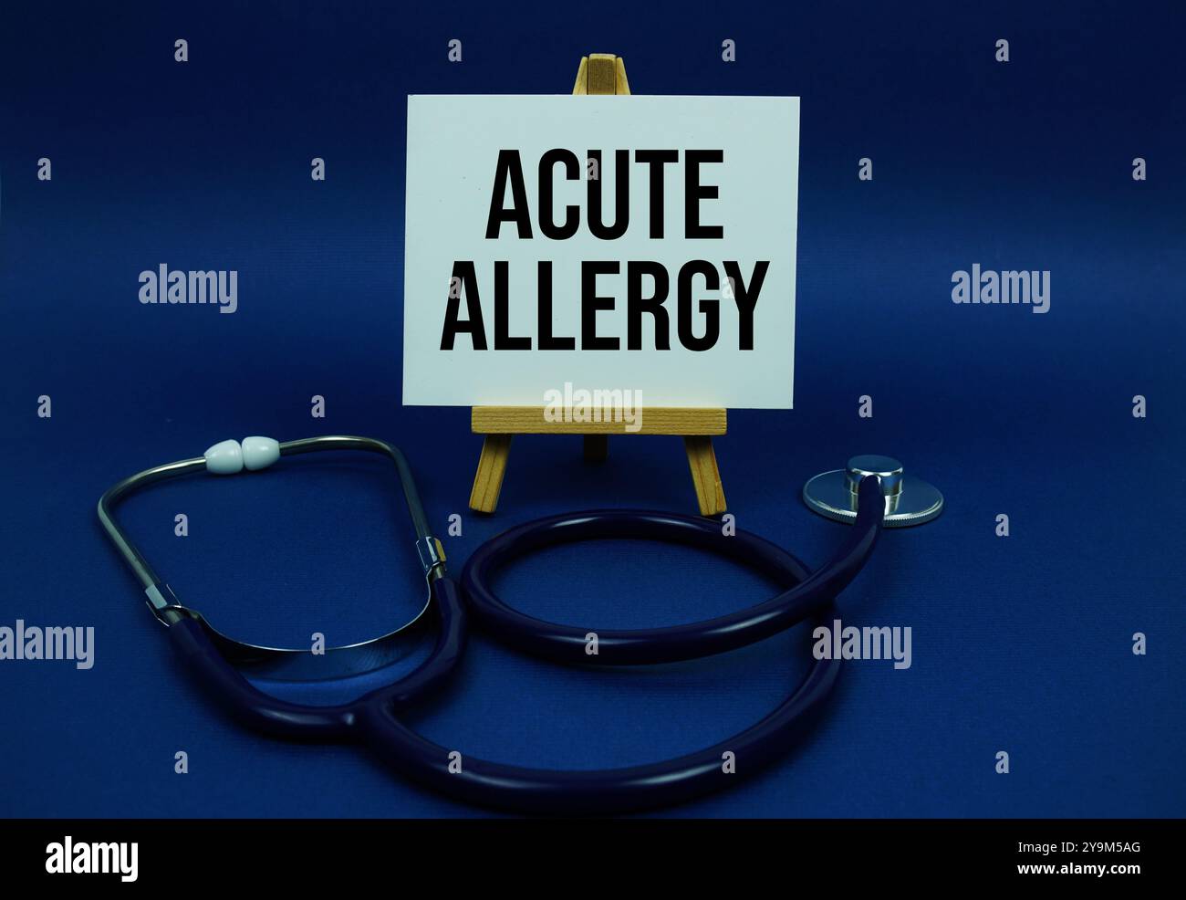 Textnachricht zu akuter Allergie auf Papierkarte mit Stethoskop auf blauem Hintergrund Stockfoto