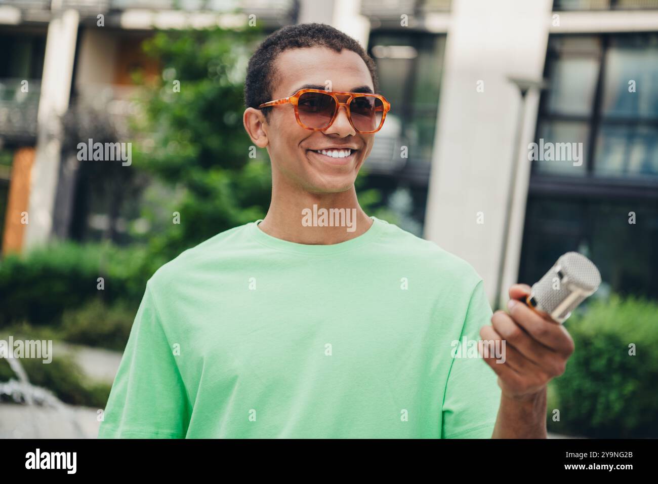 Porträt eines netten jungen Mannes Journalist halten Mikrofon Interview Wochenende Spaziergang Downtown Street draußen Stockfoto