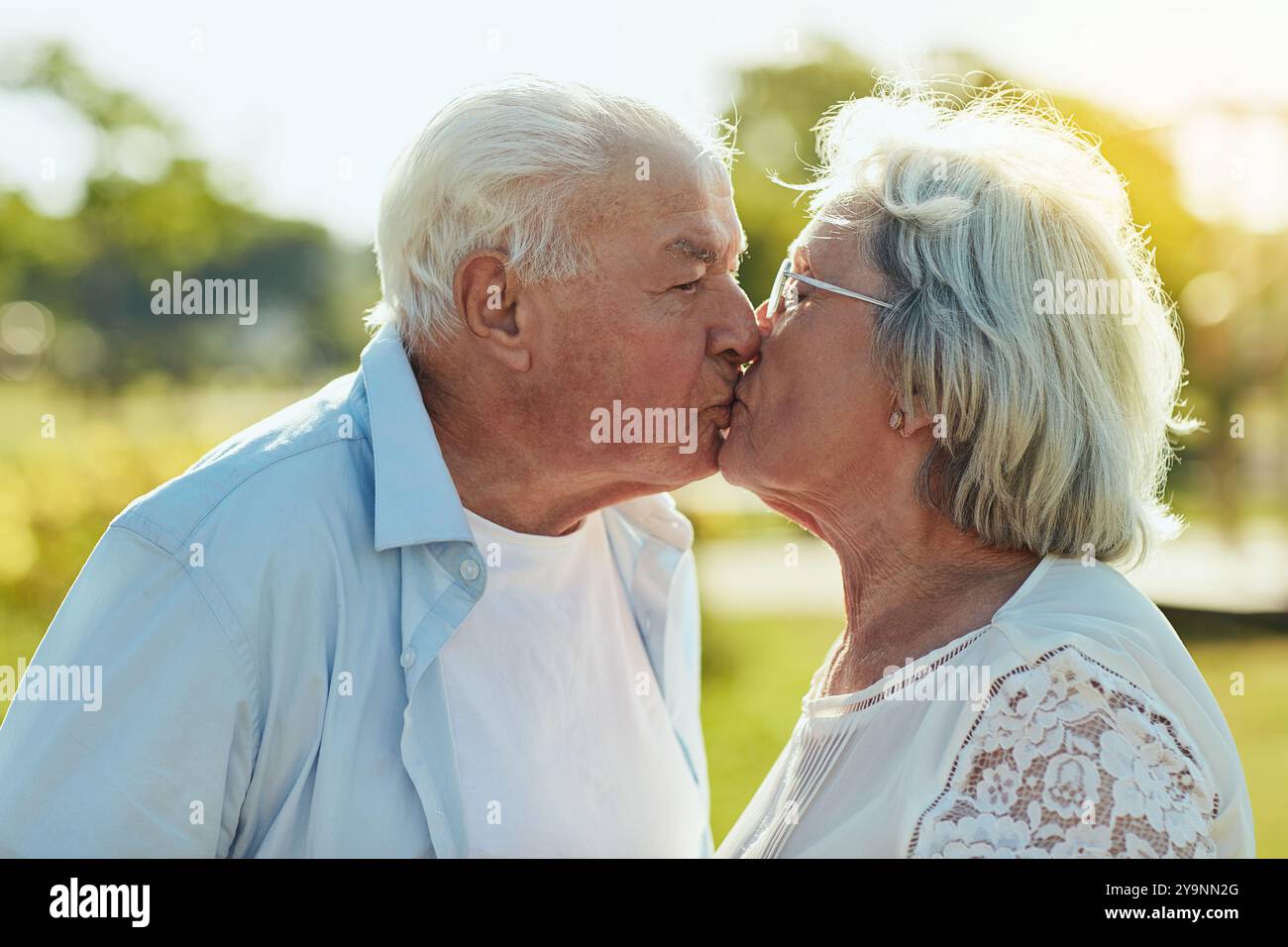 Liebe, Kuss und ältere Paare im Park mit fröhlichem Lächeln und Verbundenheit in der Natur. Senior Mann, Frau und Romantik im Garten mit Vertrauen, Unterstützung Stockfoto