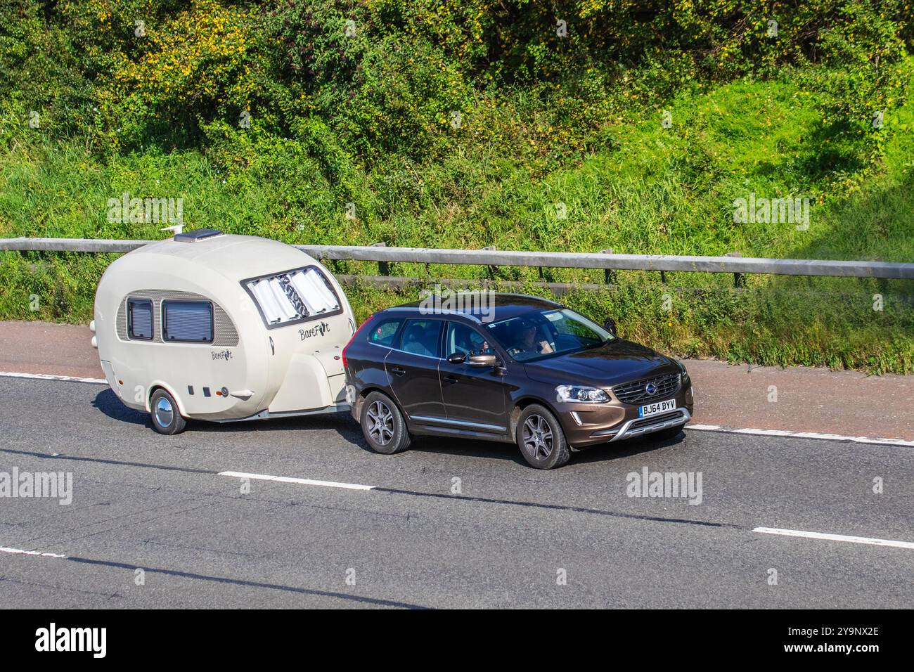 2014 Bronze Volvo XC60 SE LUX NAV D5 AWD Auto schleppt Barfuß Pod kleiner Wohnwagen auf der Autobahn M7, Großbritannien Stockfoto