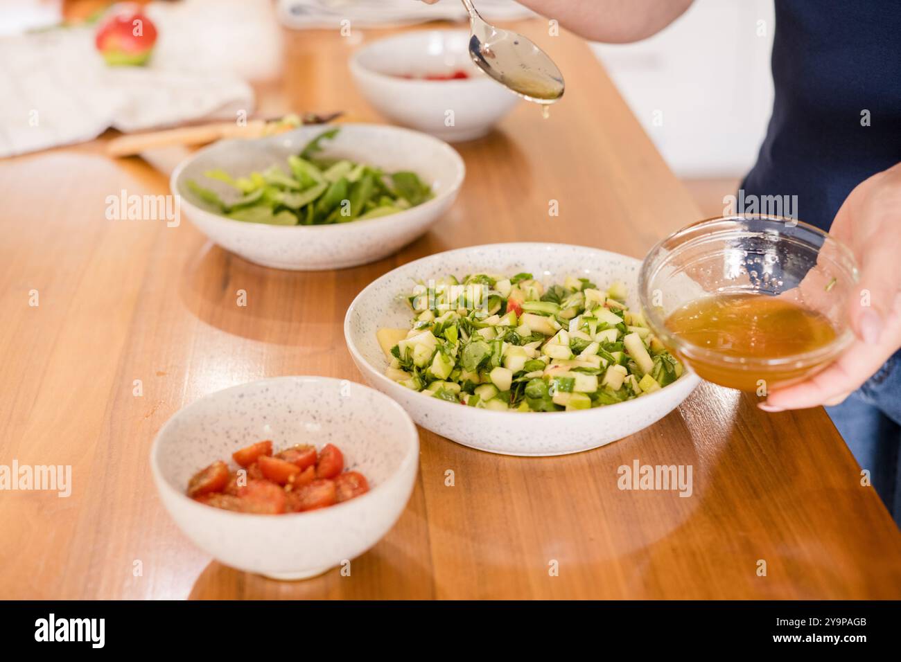 Frau fügt Dressing zu ihrem Salat hinzu Stockfoto