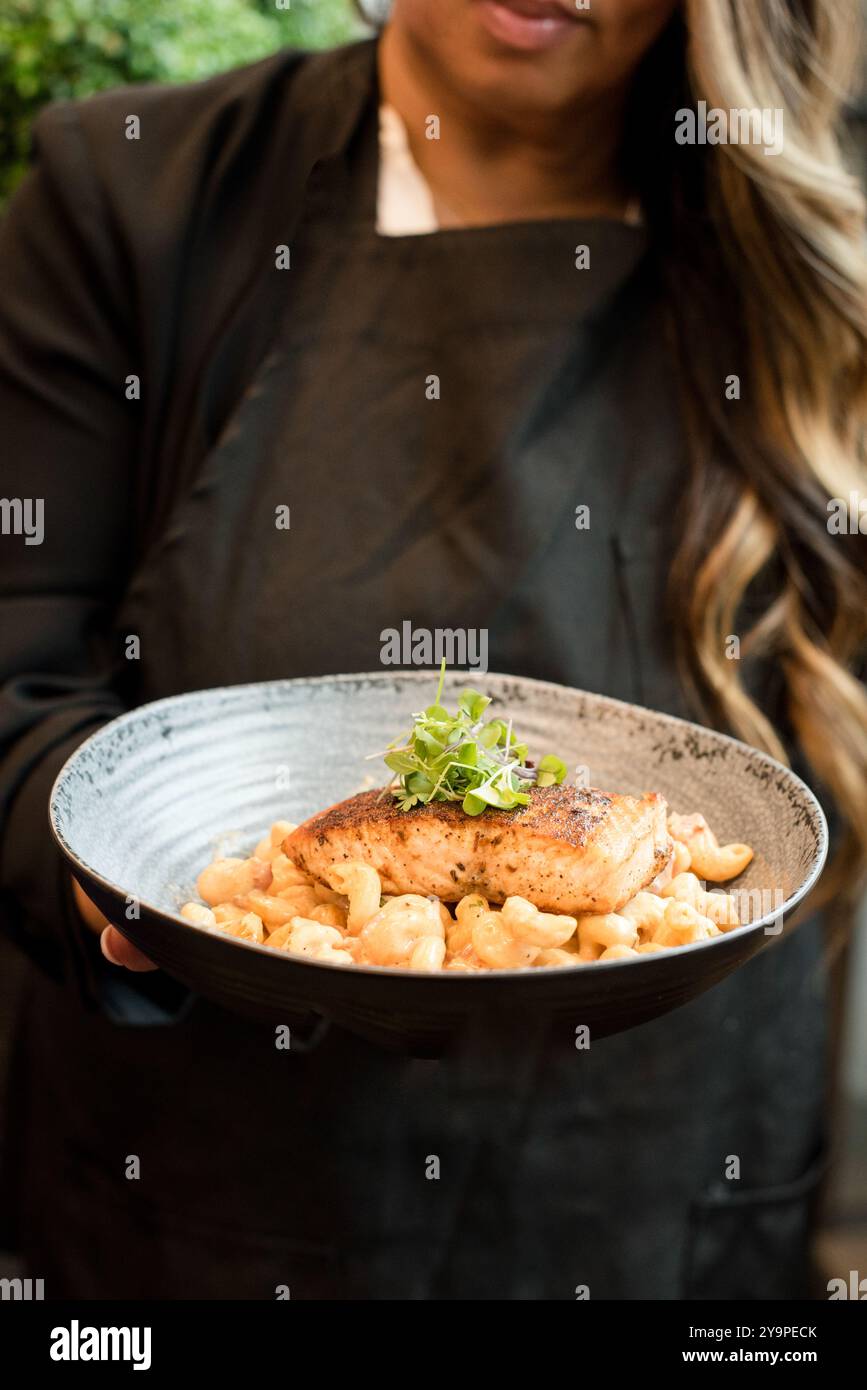 Eine Frau, die eine Schüssel mit Käse und Lachs hält Stockfoto