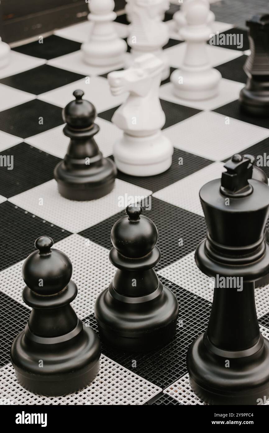 Riesige schwarz-weiße Schachfiguren auf einem karierten Outdoor-Brett Stockfoto