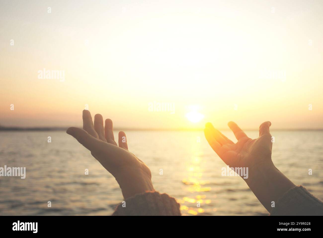 Die Person hebt die Hände zur Sonne als Zeichen der einladenden Energie und des Konzepts des Wohlbefindens Stockfoto