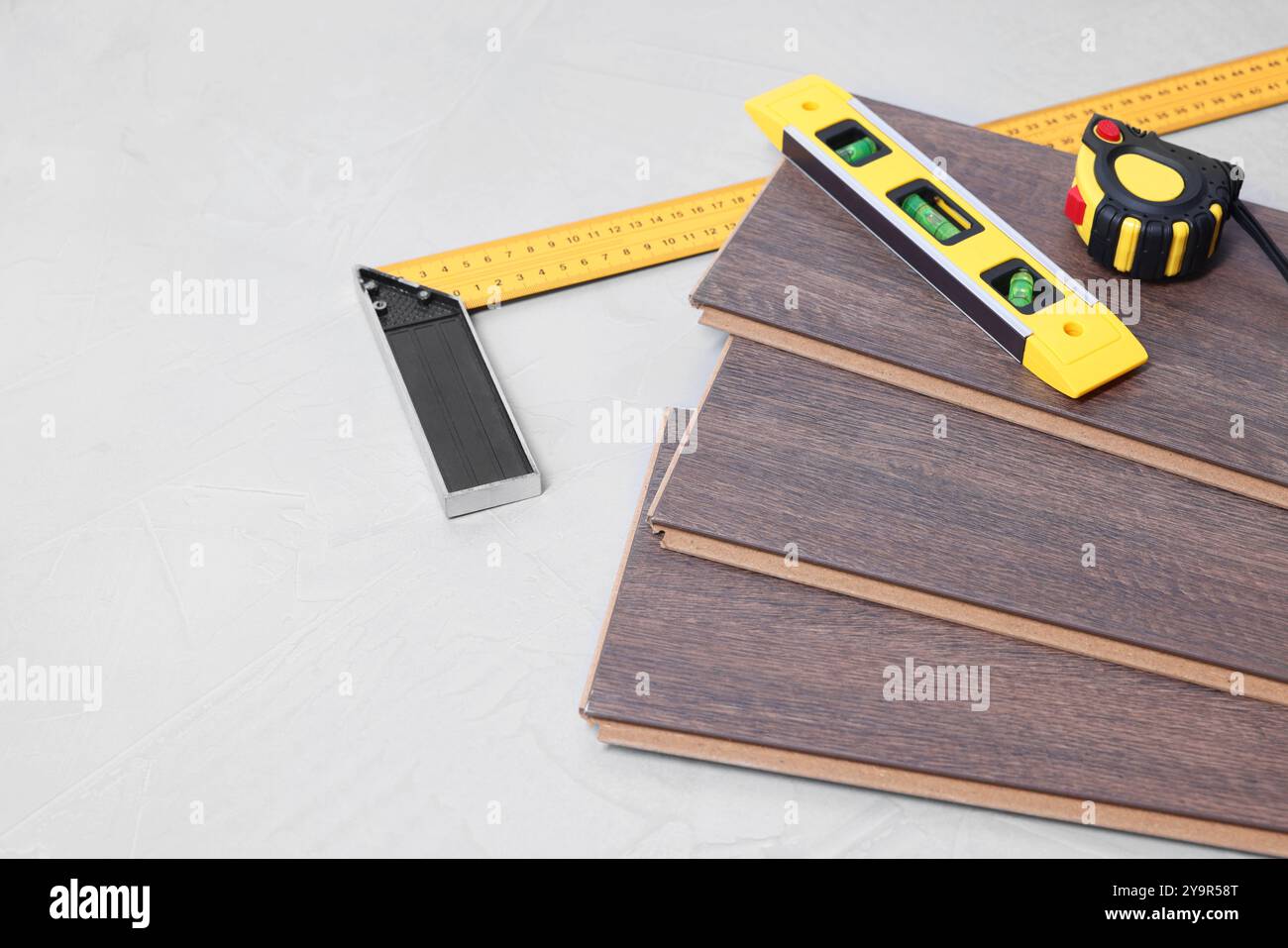 Verschiedene Messwerkzeuge und Laminatbodenstücke auf grau strukturierter Oberfläche Stockfoto