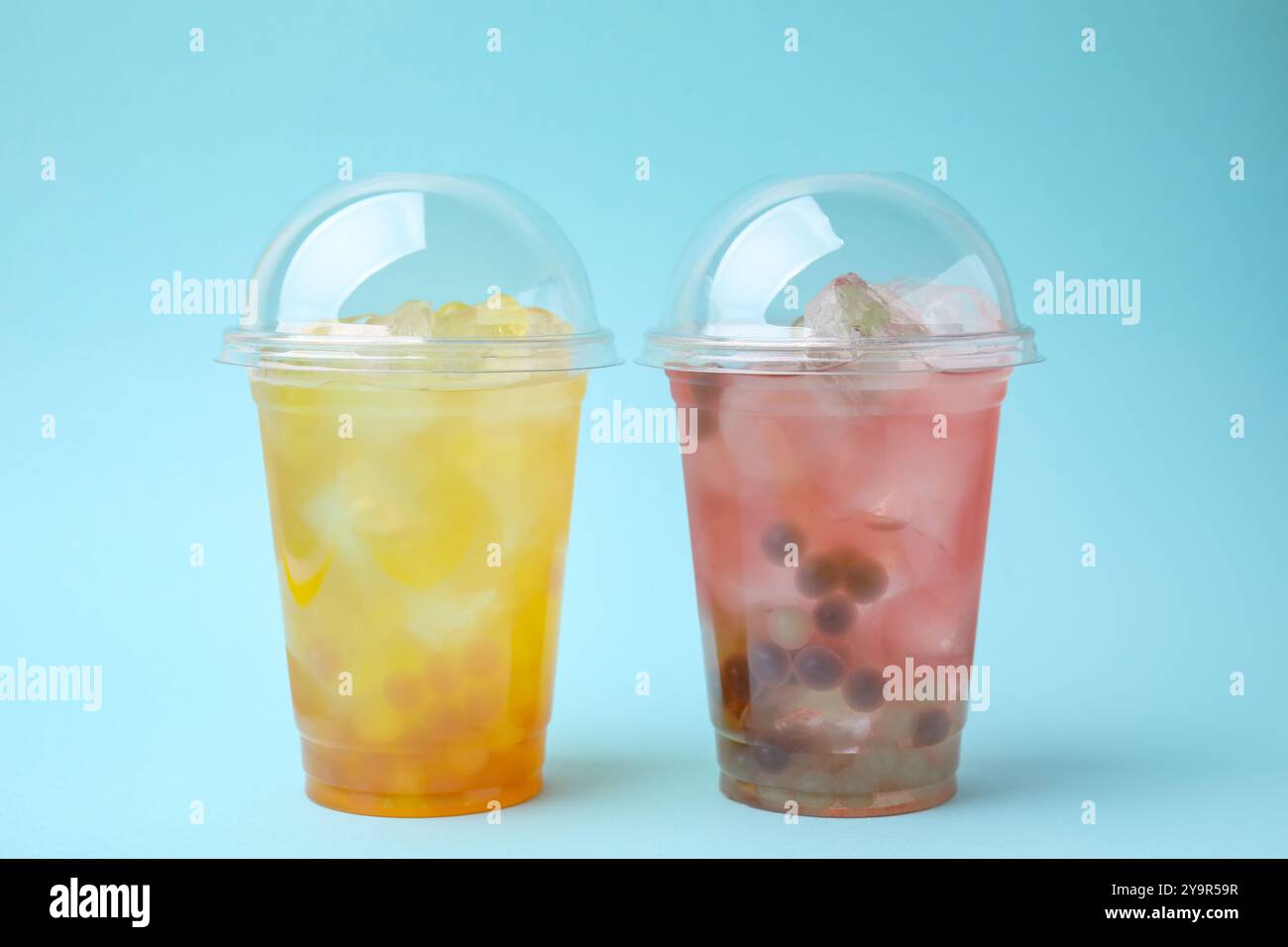 Leckerer Bubble Tee in Plastikbechern auf hellblauem Hintergrund Stockfoto