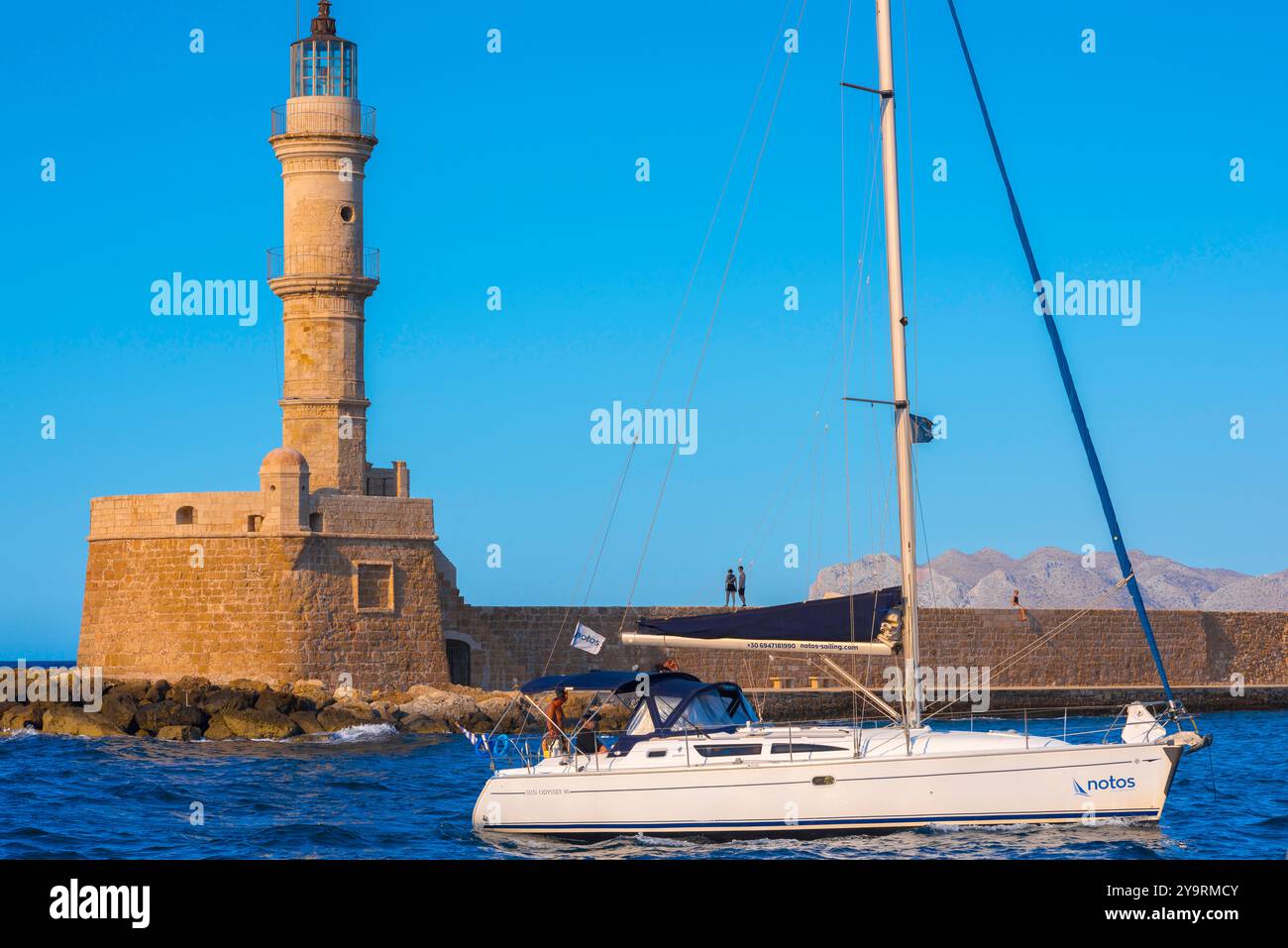 Yacht Mittelmeer, Blick auf eine Yacht, die im Sommer am venezianischen Leuchtturm vorbeifährt, der sich im Hafen der Altstadt in Chania (Hania), Kreta, Griechenland befindet Stockfoto