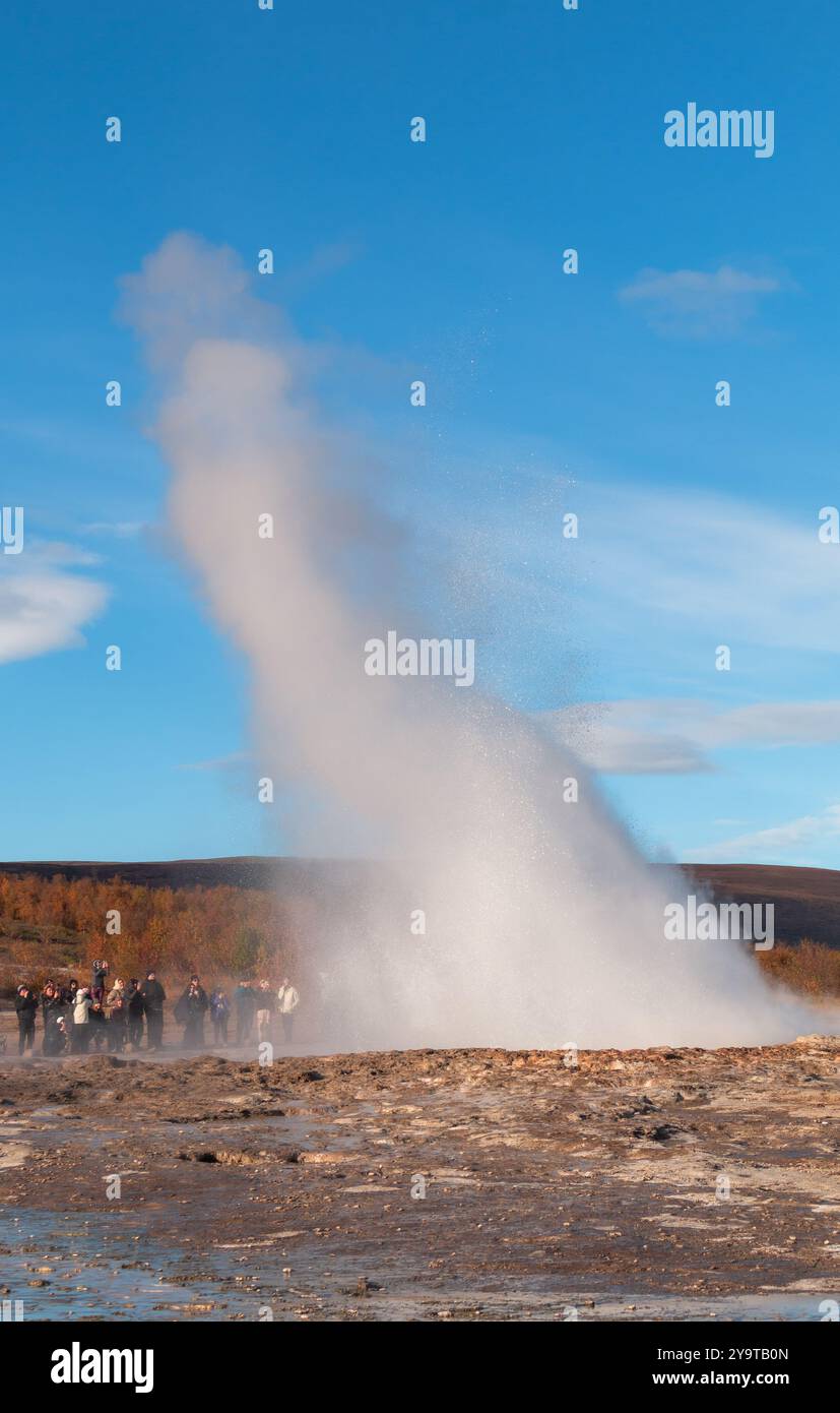 Haukadalur Valley, Island - 3. Oktober 2024: Eine kleine Menschenmenge beobachtet, wie Strokkur Geysir Wasser sprüht. Stockfoto