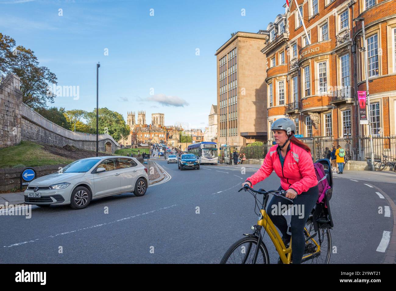 Radfahrerinnen fahren auf einem Einbahnsystem auf einer Hauptstraße innerhalb der ummauerten Stadt York und vor dem Grand Hotel in Yorkshire, England. Stockfoto
