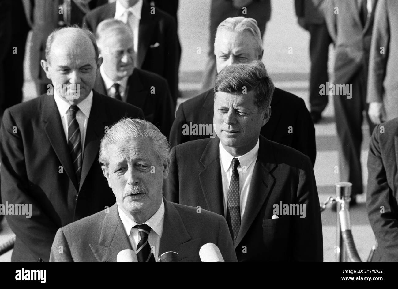 Der britische Premierminister Harold Macmillan hält während der Ankunftszeremonien zu seinen Ehren, von links nach rechts hinter MacMillan: Dean Rusk, US-Außenminister; Sir Norman Brook, Minister des Kabinetts des Premierministers; US-Präsident John F. Kennedy; David K. E. Bruce, US-Botschafter in Großbritannien; Andrews Air Force Base, Prince George's County, Maryland, USA, Cecil Stoughton, Fotos Des Weißen Hauses, 27. April 1962 Stockfoto