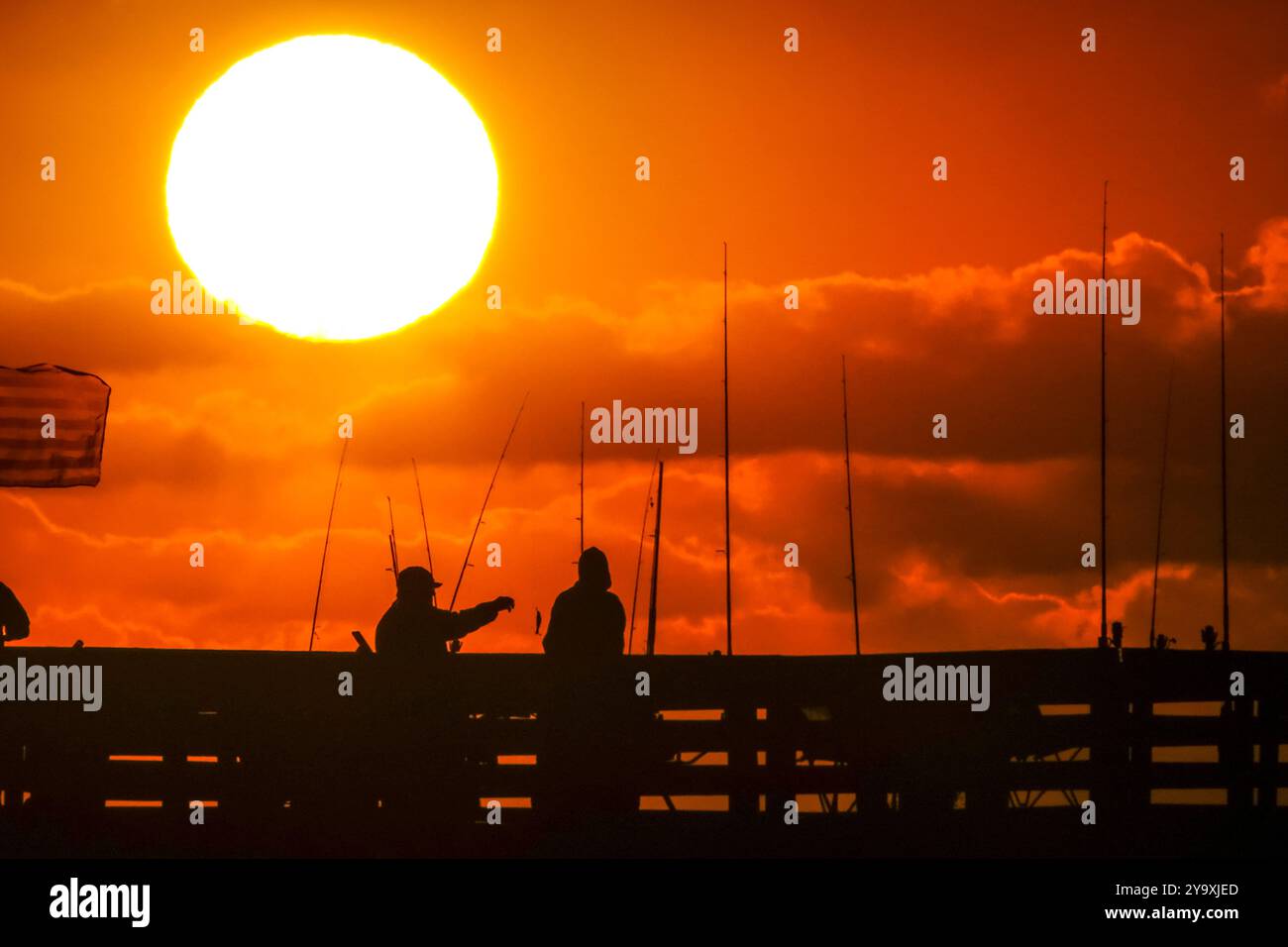 Isle Of Palms, Usa. Oktober 2024. Fisherman Silhouetten von einem dramatischen Sonnenaufgang werfen ihre Linien vor der Isle of Palms Pier am 11. Oktober 2024 in Isle of Palms, South Carolina. Hurrikan Milton zog 400 Meilen weiter nach Süden, führte aber herbstliches Wetter entlang der Küste, während die Stürme aufwachen. Quelle: Richard Ellis/Richard Ellis/Alamy Live News Stockfoto