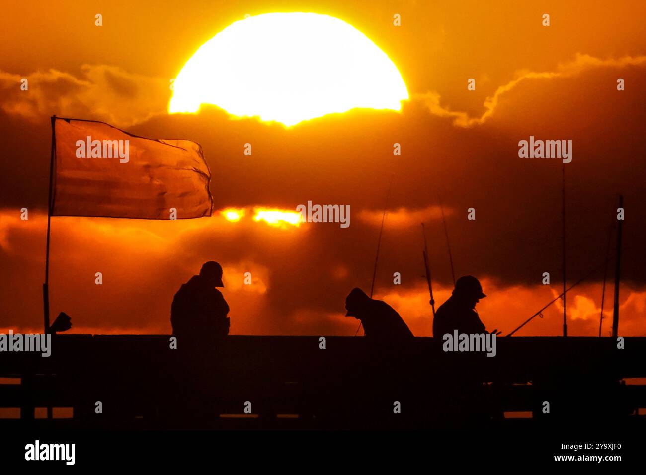 Isle Of Palms, Usa. Oktober 2024. Fisherman Silhouetten von einem dramatischen Sonnenaufgang werfen ihre Linien vor der Isle of Palms Pier am 11. Oktober 2024 in Isle of Palms, South Carolina. Hurrikan Milton zog 400 Meilen weiter nach Süden, führte aber herbstliches Wetter entlang der Küste, während die Stürme aufwachen. Quelle: Richard Ellis/Richard Ellis/Alamy Live News Stockfoto