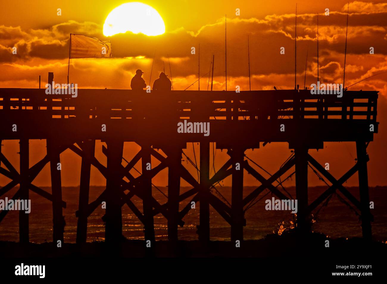 Isle Of Palms, Usa. Oktober 2024. Fisherman Silhouetten von einem dramatischen Sonnenaufgang werfen ihre Linien vor der Isle of Palms Pier am 11. Oktober 2024 in Isle of Palms, South Carolina. Hurrikan Milton zog 400 Meilen weiter nach Süden, führte aber herbstliches Wetter entlang der Küste, während die Stürme aufwachen. Quelle: Richard Ellis/Richard Ellis/Alamy Live News Stockfoto