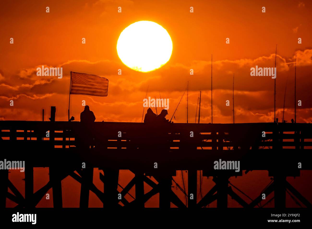 Isle Of Palms, Usa. Oktober 2024. Fisherman Silhouetten von einem dramatischen Sonnenaufgang werfen ihre Linien vor der Isle of Palms Pier am 11. Oktober 2024 in Isle of Palms, South Carolina. Hurrikan Milton zog 400 Meilen weiter nach Süden, führte aber herbstliches Wetter entlang der Küste, während die Stürme aufwachen. Quelle: Richard Ellis/Richard Ellis/Alamy Live News Stockfoto