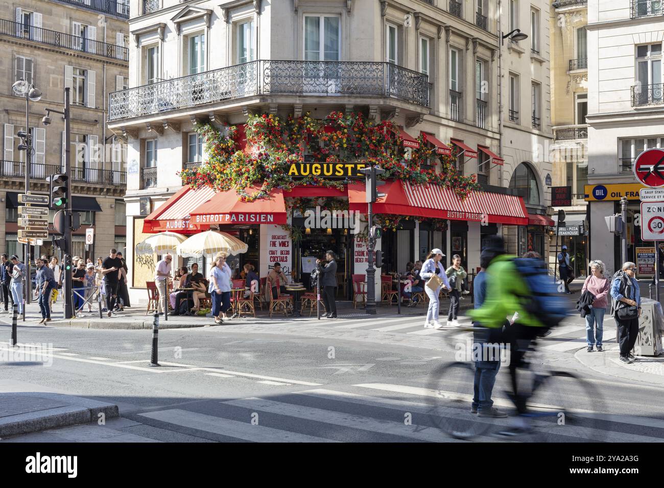 Schnappschuss eines lebhaften Straßencafés mit üppigen Blumenarrangements und Radfahrern, Paris Stockfoto