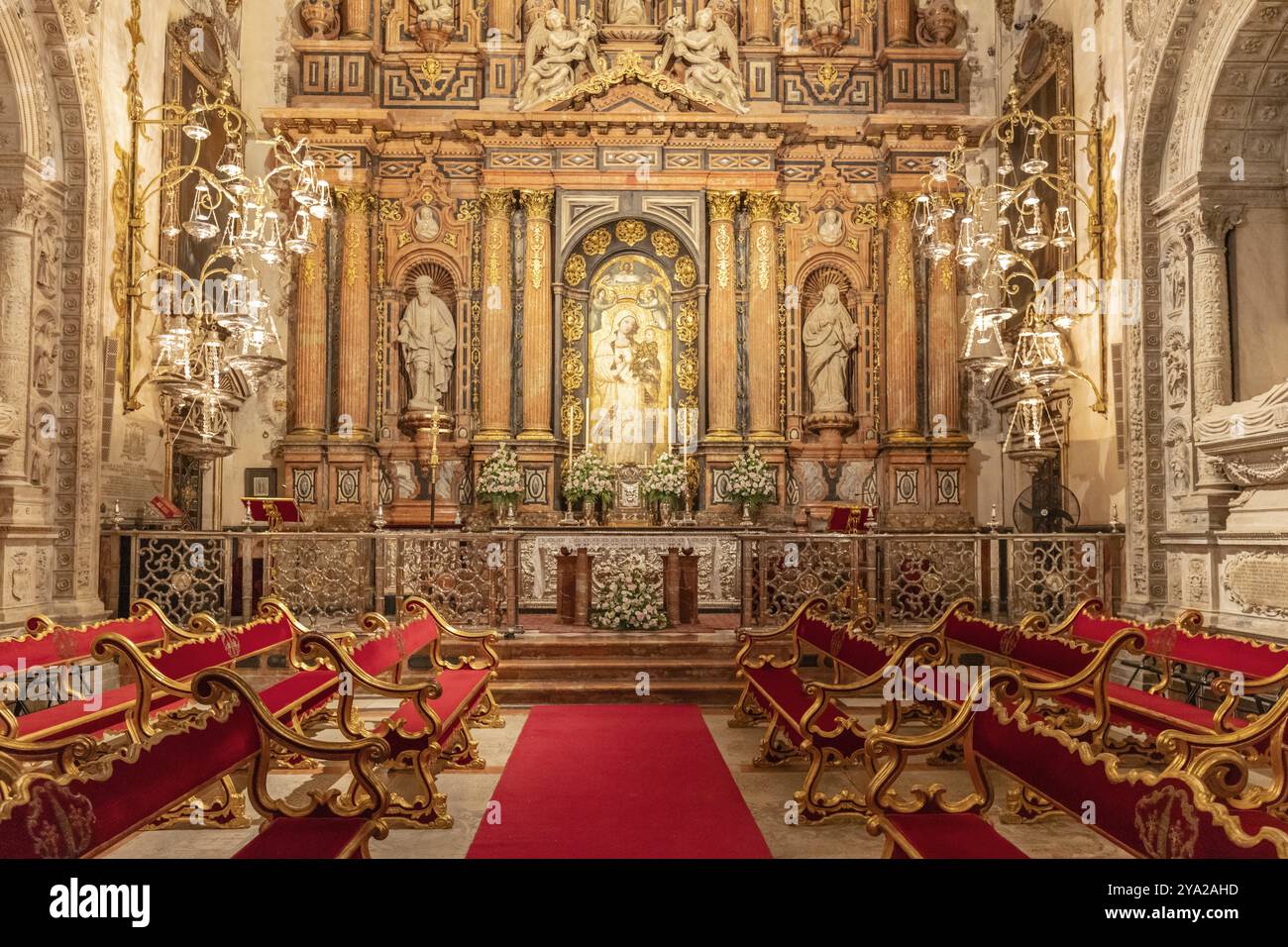 Opulente Kapelle mit prächtigem Altar und eleganten roten Bänken, Sevilla Stockfoto