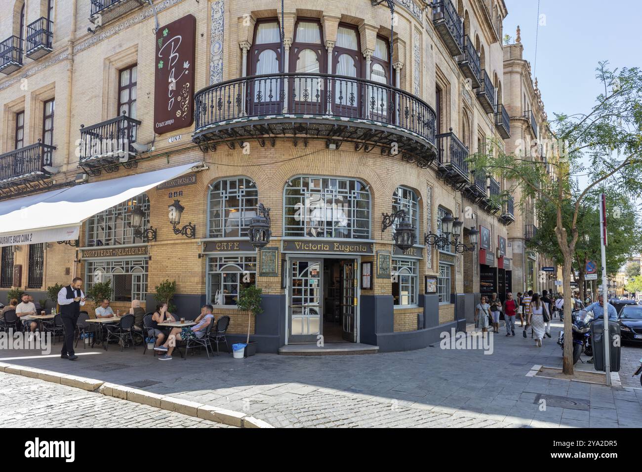 Menschen sitzen in einem Straßencafé vor einem historischen Gebäude in einer städtischen Umgebung, Sevilla Stockfoto