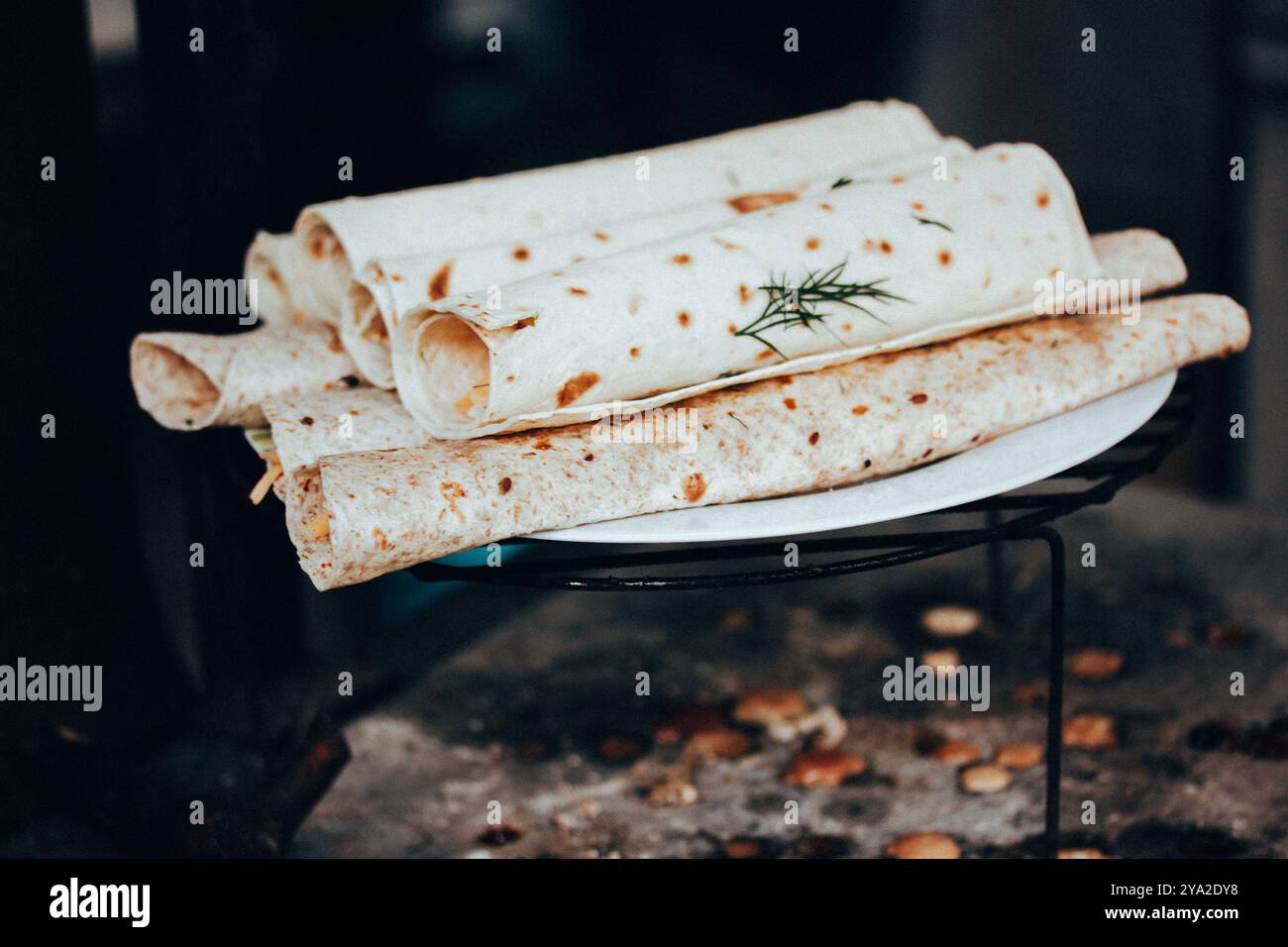 Fladenbrot gerollt und mit Käse und Gemüse gefüllt. Grillzubereitung im Freien. Vegetarisches Streetfood auf einem Metallgitter aus nächster Nähe. Stockfoto