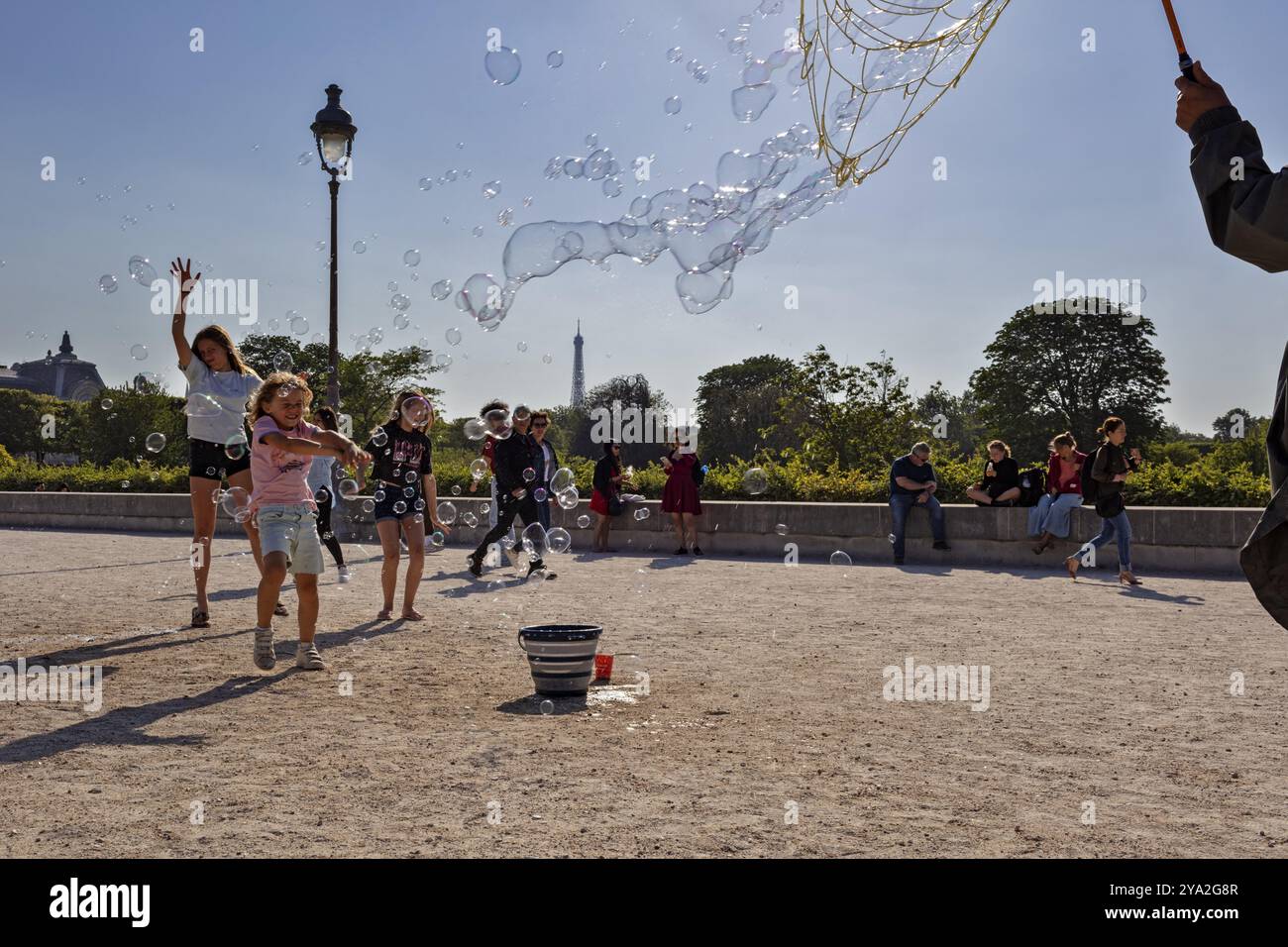 Glückliche Kinder spielen mit fliegenden Blasen in einem sonnigen Park, Paris Stockfoto