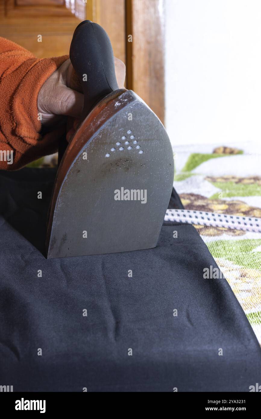 Nahaufnahme der Hände der Frau, die bügelt. Hände einer Seniorin, die ein Handtuch bügelt Stockfoto