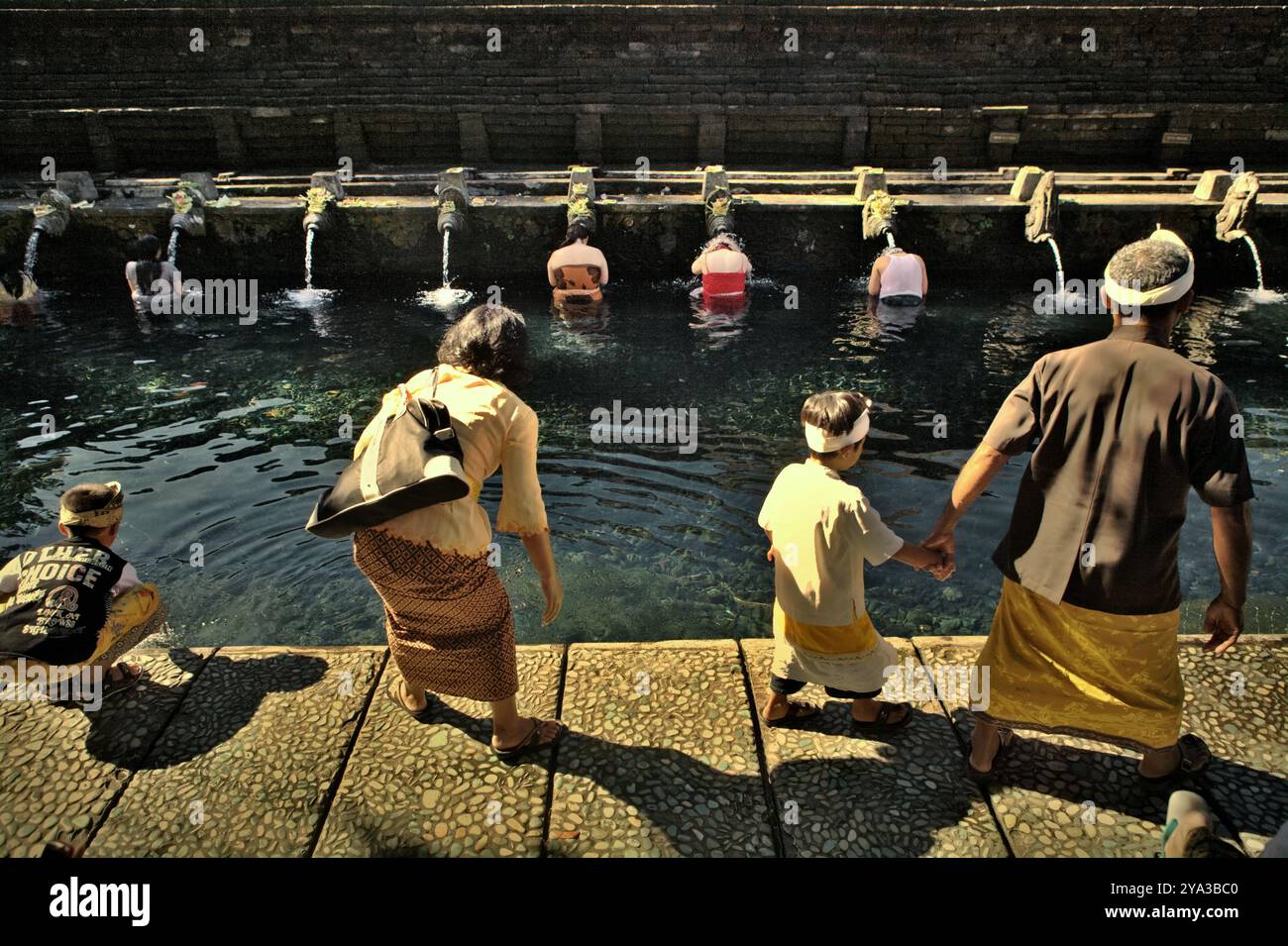 Eine balinesische Familie, die den Swimmingpool des Tirta Empul-Tempels in Templaksiring, Gianyar, Bali, Indonesien besucht. Stockfoto