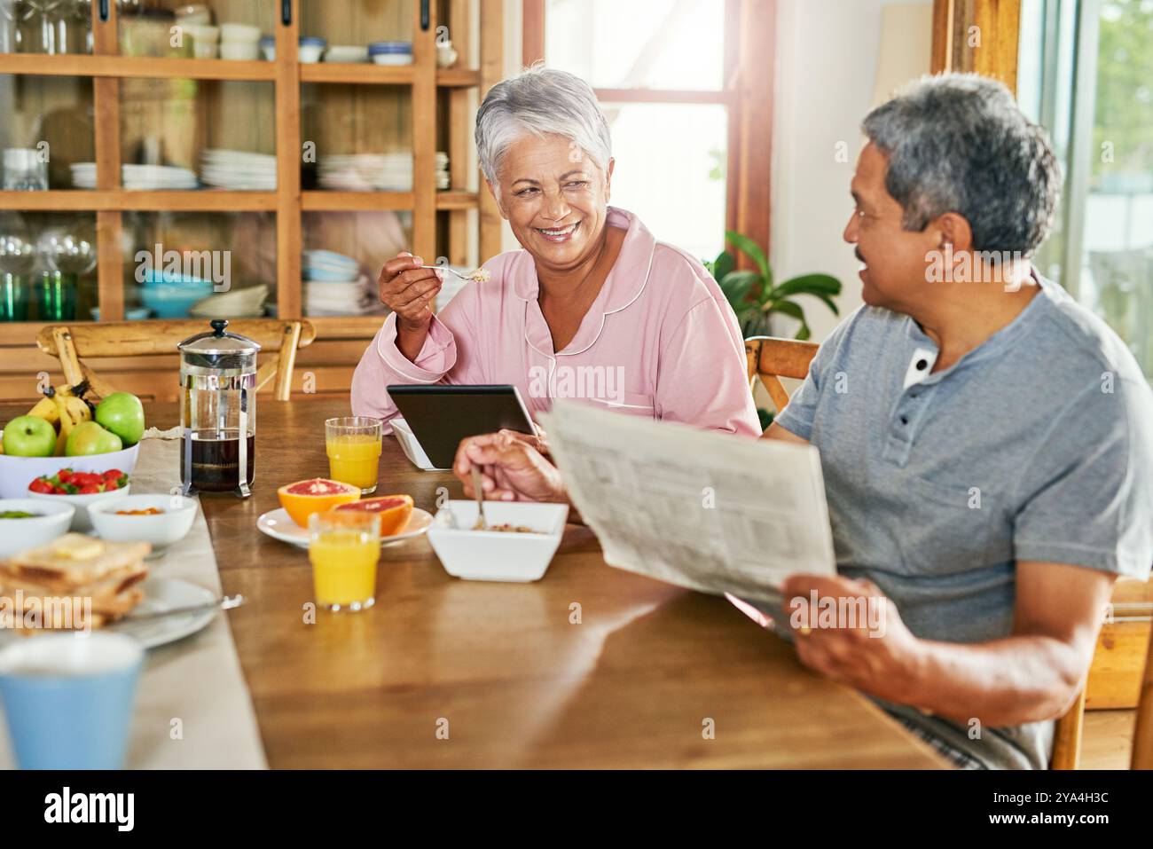 Zeitung, Frühstück und Seniorenpaar mit Tablette, gesund essen zu Hause und Wellness und Essen zusammen. Glücklich, Unterhaltung und alter Mann und Frau Stockfoto