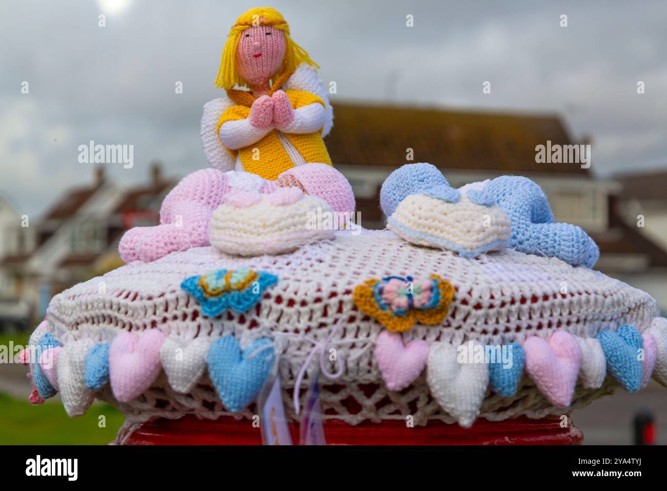 Poole, Dorset, Großbritannien. Oktober 2024. Ein gestrickter Briefkasten-Topper erscheint auf einem roten Briefkasten in Poole, Dorset, in Anerkennung der Baby Loss Awareness Week (9.-15. Oktober), jetzt in ihrem 22. Jahr, und zeigt Unterstützung für Familien, die von Babyverlust betroffen sind und erinnert sich an Babys, die leider nicht mehr bei uns sind. Quelle: Carolyn Jenkins/Alamy Live News Stockfoto