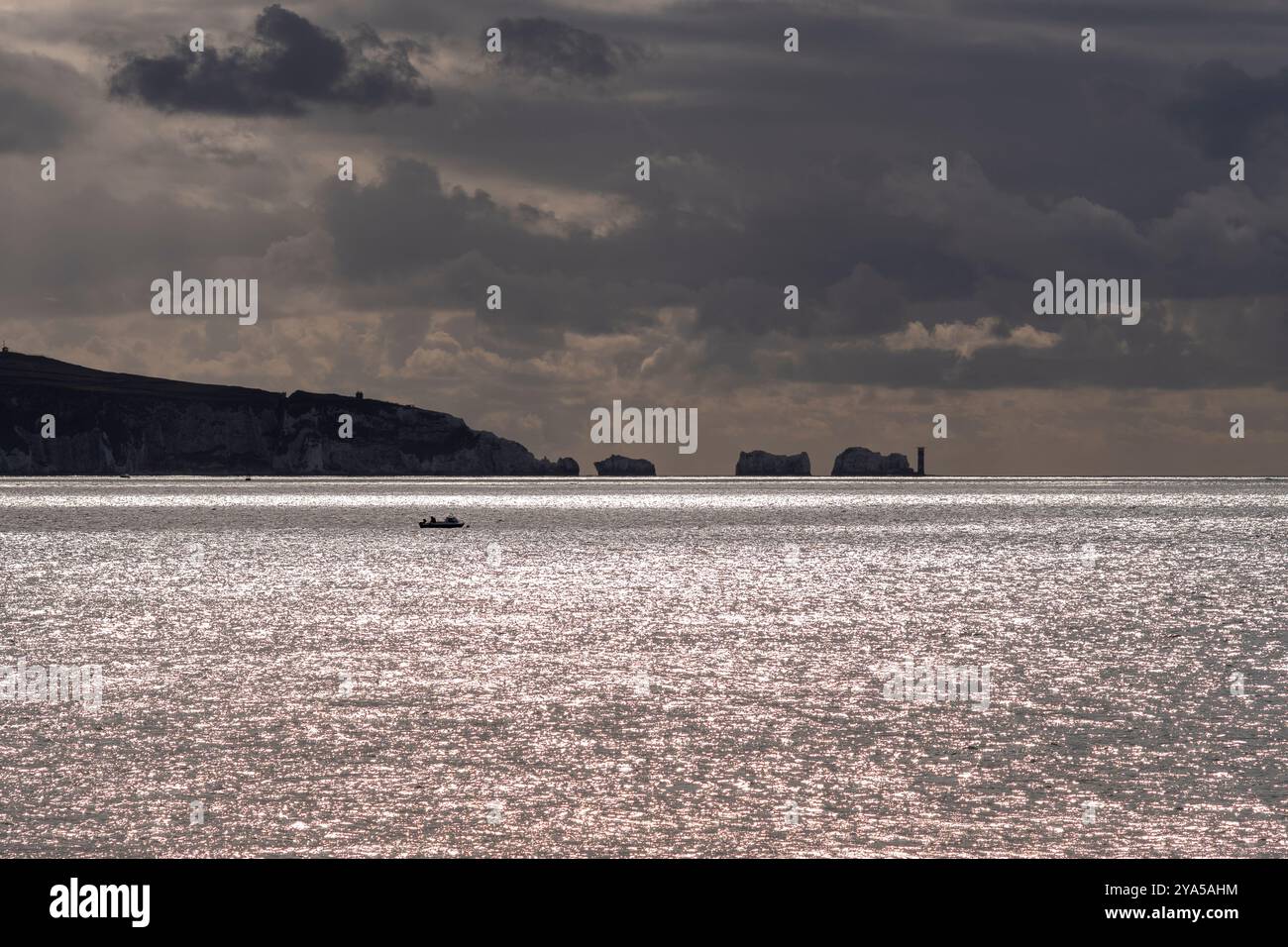 Needles Point und Leuchtturm auf der Isle of Wight, Silhouette von hellem Licht auf dem Meer und dunklen Wolken, England, Großbritannien, Oktober Stockfoto