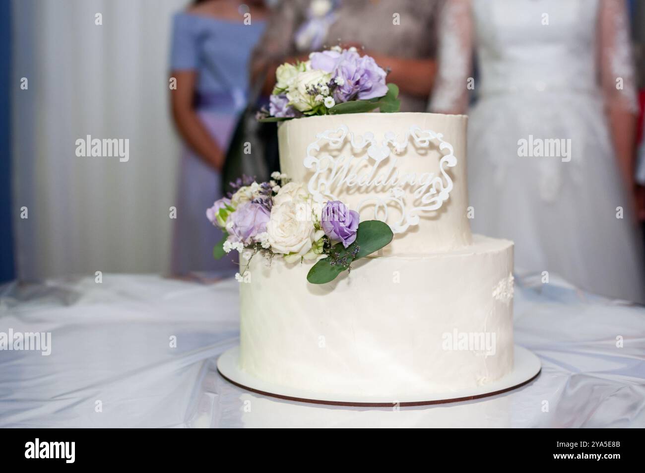Eleganter mehrstöckiger Hochzeitstorte mit frischen Blumen und kompliziertem Design. Stockfoto