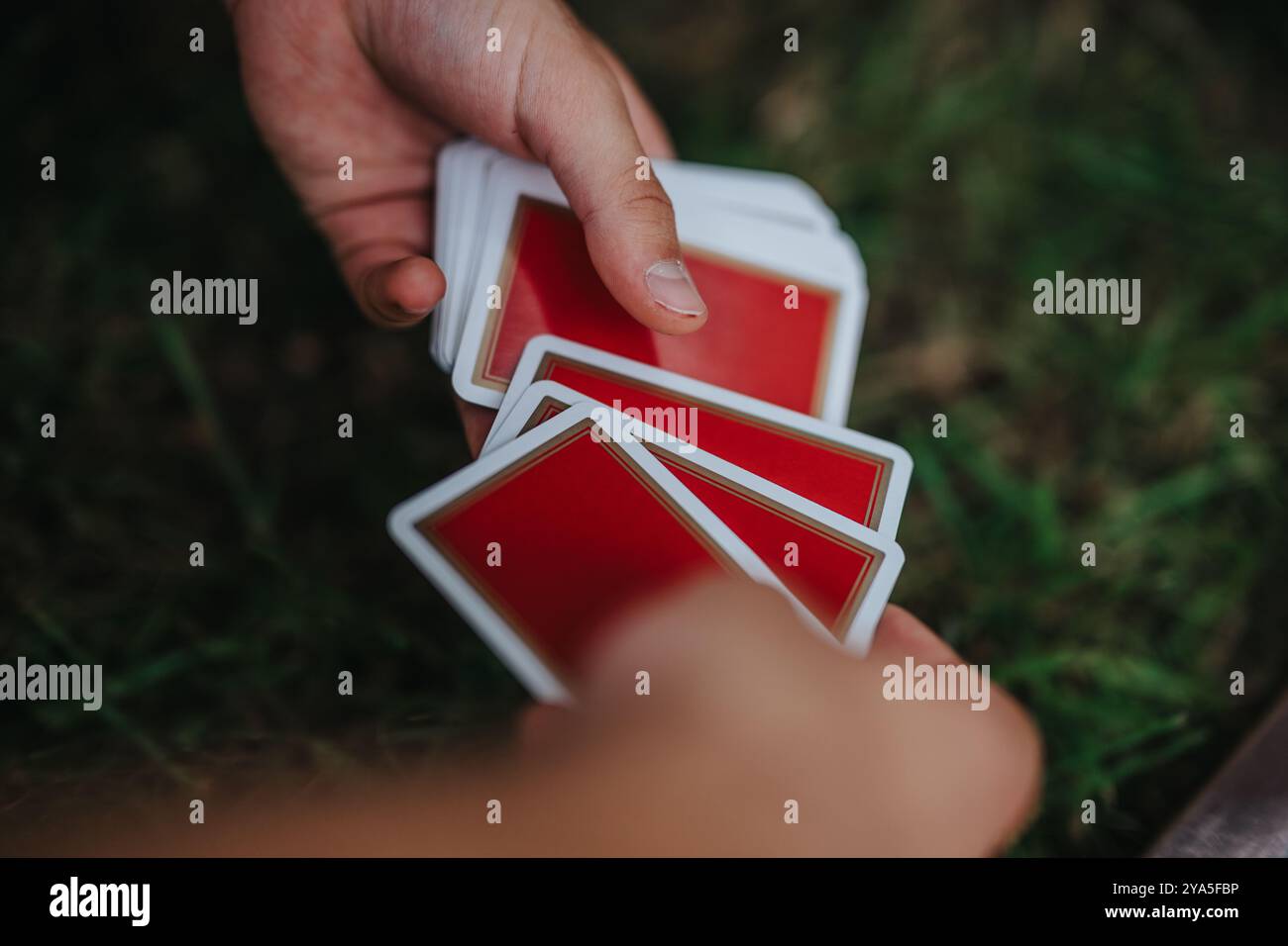 Die Person handhabt gekonnt Spielkarten in einer entspannten Umgebung im Freien Stockfoto