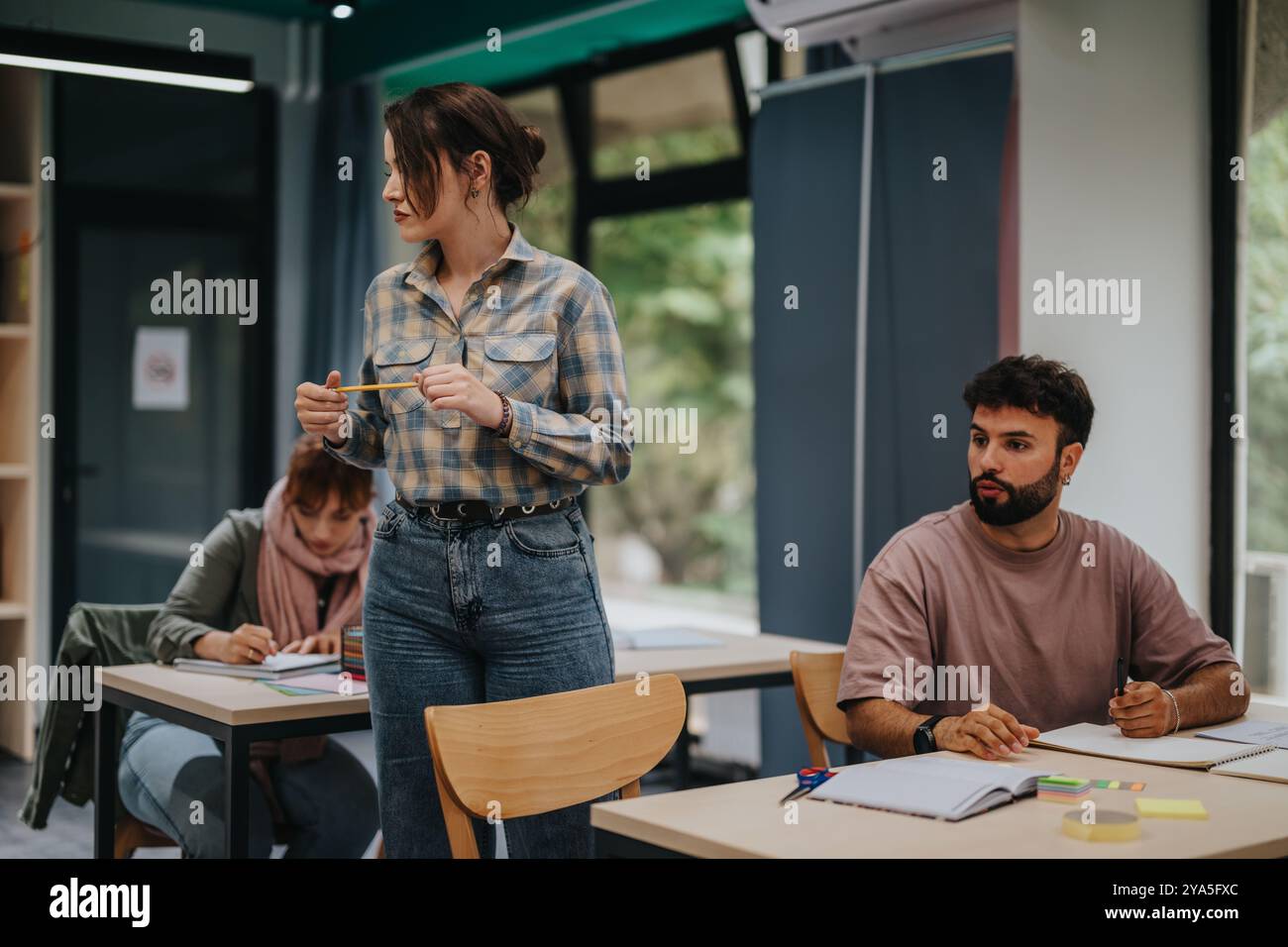 Schüler, die an einer Lektion in einem gemütlichen Klassenzimmer teilnehmen Stockfoto