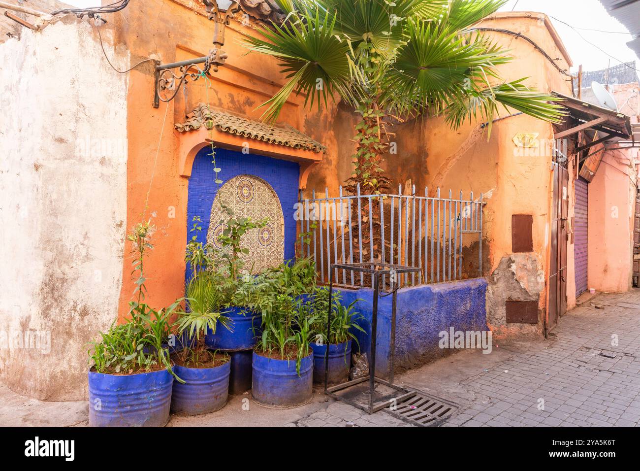 In einer Ecke der Medina von Marrakesch hebt sich diese grüne Ecke mit dunkelblauer Farbe von der rot-ockerfarbenen Umgebung ab Stockfoto