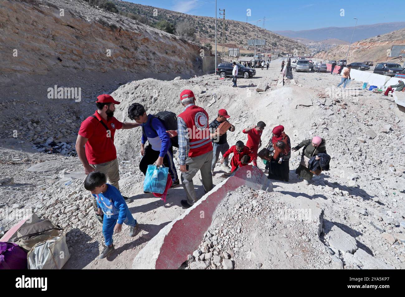 Grenzübergang Masnaa, Libanon. Oktober 2024. Dieses Foto zeigt Vertriebene aus dem Libanon, die ein Loch auf der Straße überqueren, das durch einen israelischen Luftangriff in der Nähe des Grenzübergangs Masnaa im Libanon am 11. Oktober 2024 verursacht wurde. Vor etwa einer Woche traf der israelische Luftangriff die Grenze zwischen Syrien und Libanon, bekannt als Jdeidat-Jabous-Überquerung in Syrien und Masnaa-Überquerung im Libanon, eine wichtige Transitroute, die von Zehntausenden libanesischen Flüchtlingen und syrischen Bürgern genutzt wird, die vor dem israelischen Angriff im Libanon fliehen. Quelle: Bilal Jawich/Xinhua/Alamy Live News Stockfoto