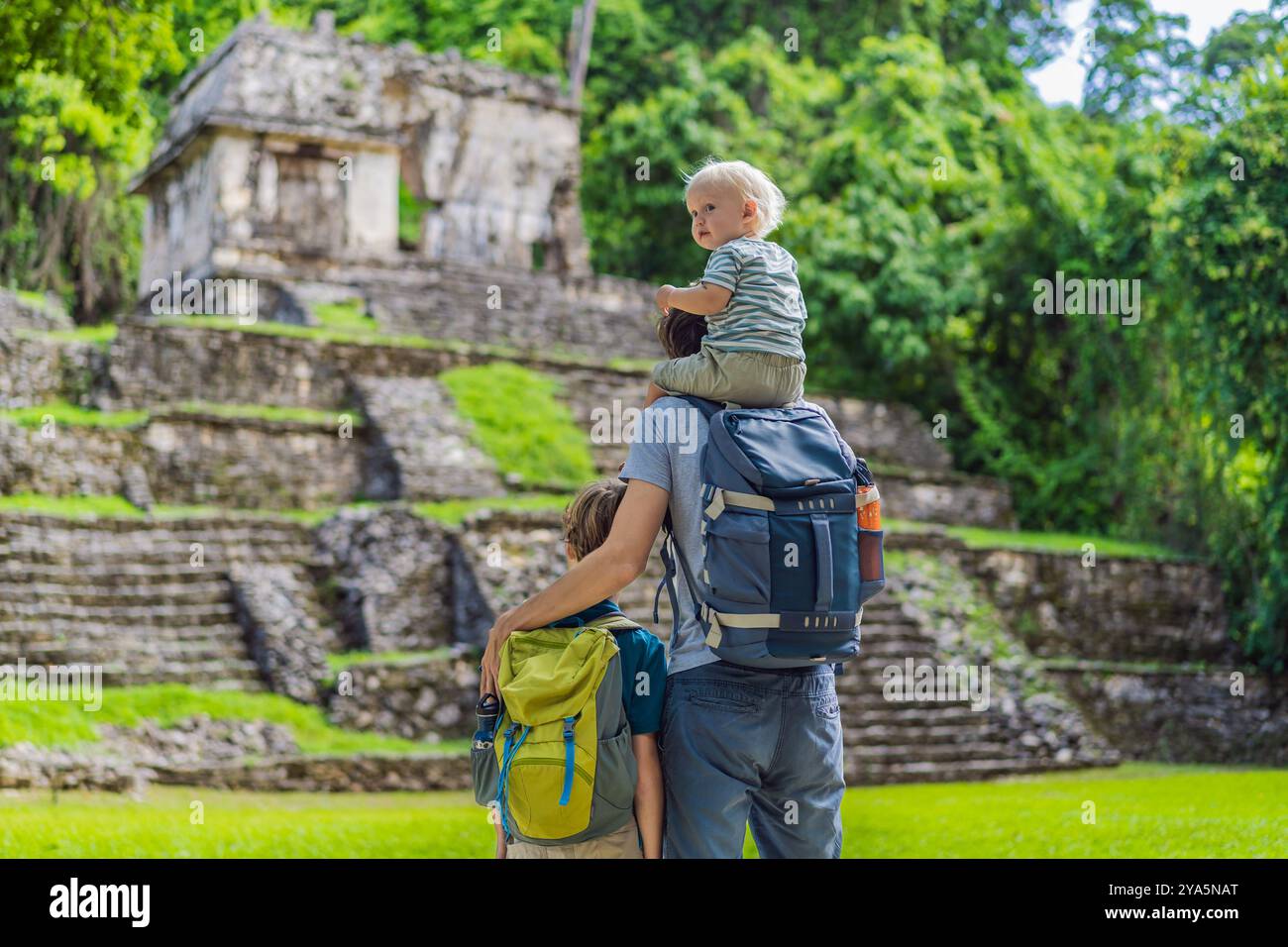 Vater mit seinem Kleinkind und seinen Söhnen im Teenageralter erkunden die alten Pyramiden von Palenque, Mexiko, umgeben von dichtem Dschungel. Kulturerbe und Stockfoto