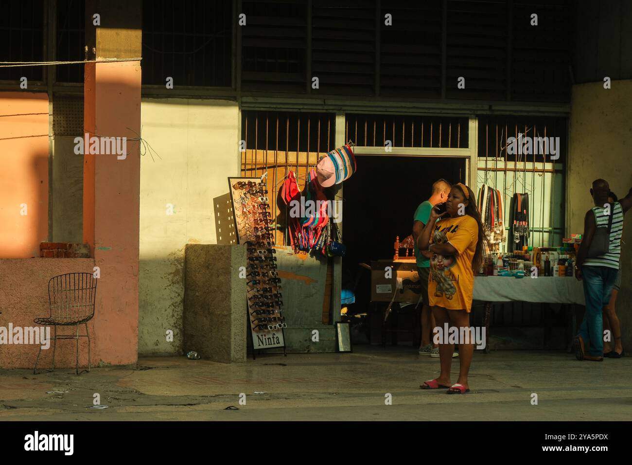 Havanna, Kuba, 2024. April 01. Kubanische Frau auf dem Handy vor einem lokalen Geschäft, das tägliche Waren und Souvenirs verkauft. Kuba steht jetzt vor einer Wirtschaftskrise. Stockfoto