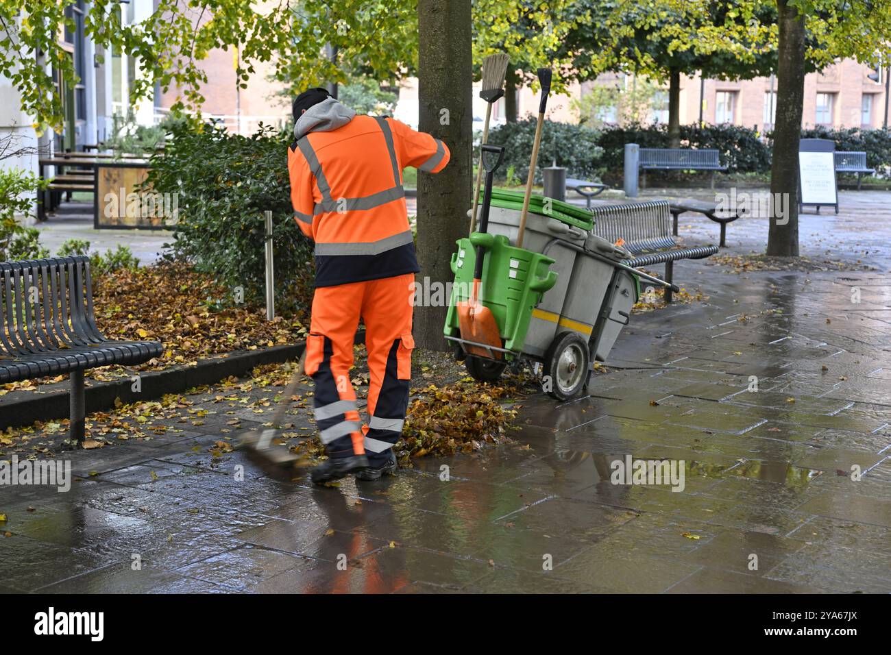 Ratsmitglied fegt Herbstlaub auf dem Stadtplatz in Bristol, Großbritannien Stockfoto